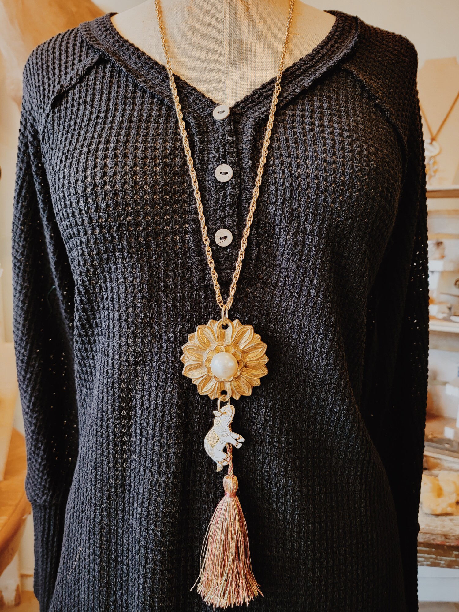 This beautiful necklace was hand crafted! It has a vintage floral medallion as the pendant with a pearl center, and a lovely white, gold, and black elephant hangs from it. The tassel is 4 inches long, and the chain is 34 inches.