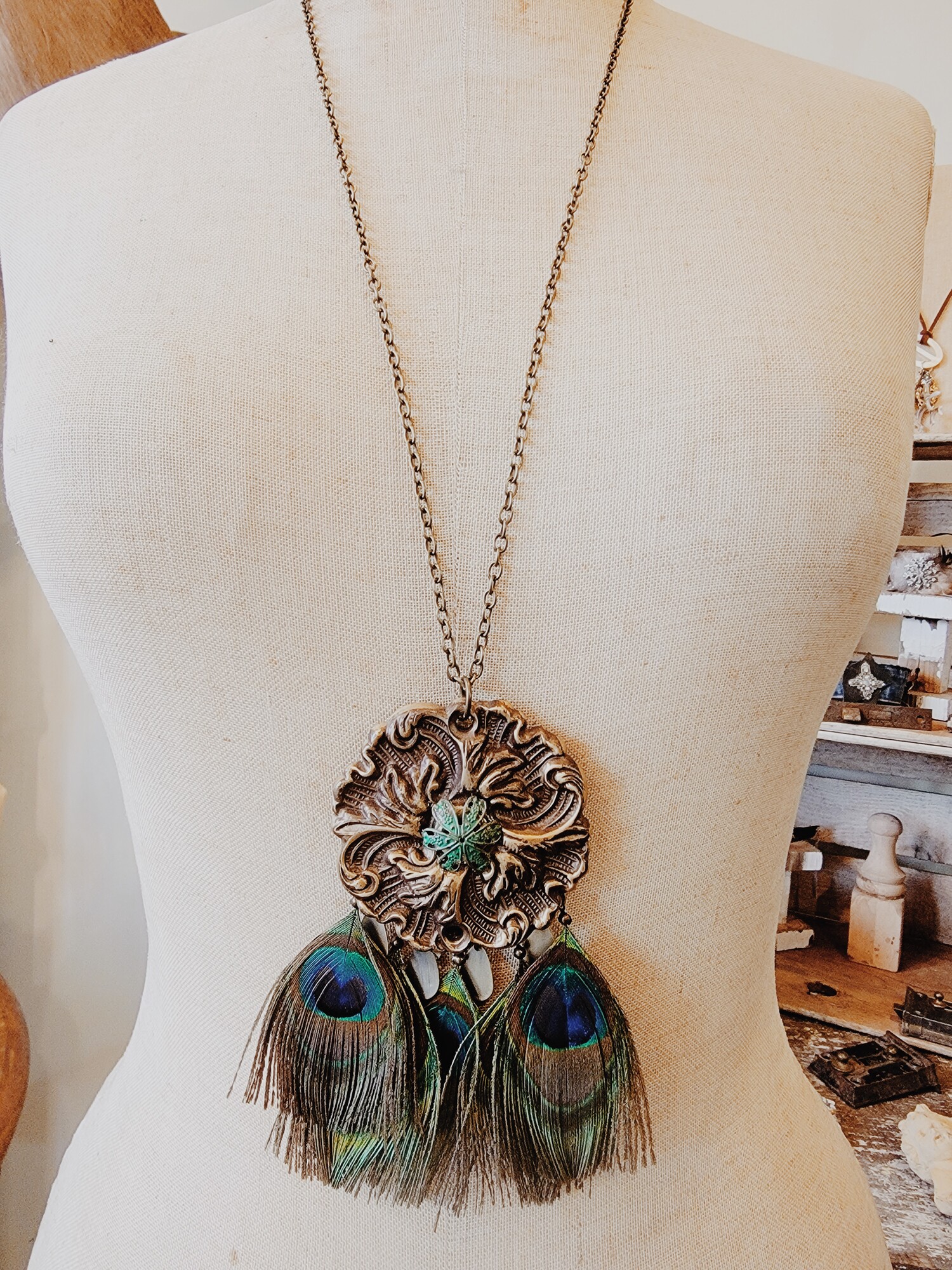 This beautiful necklace was hand crafted! The artist used a vintage floral medallion for the pendant and attached faux peacock feathers.
Chain: 32 Inches