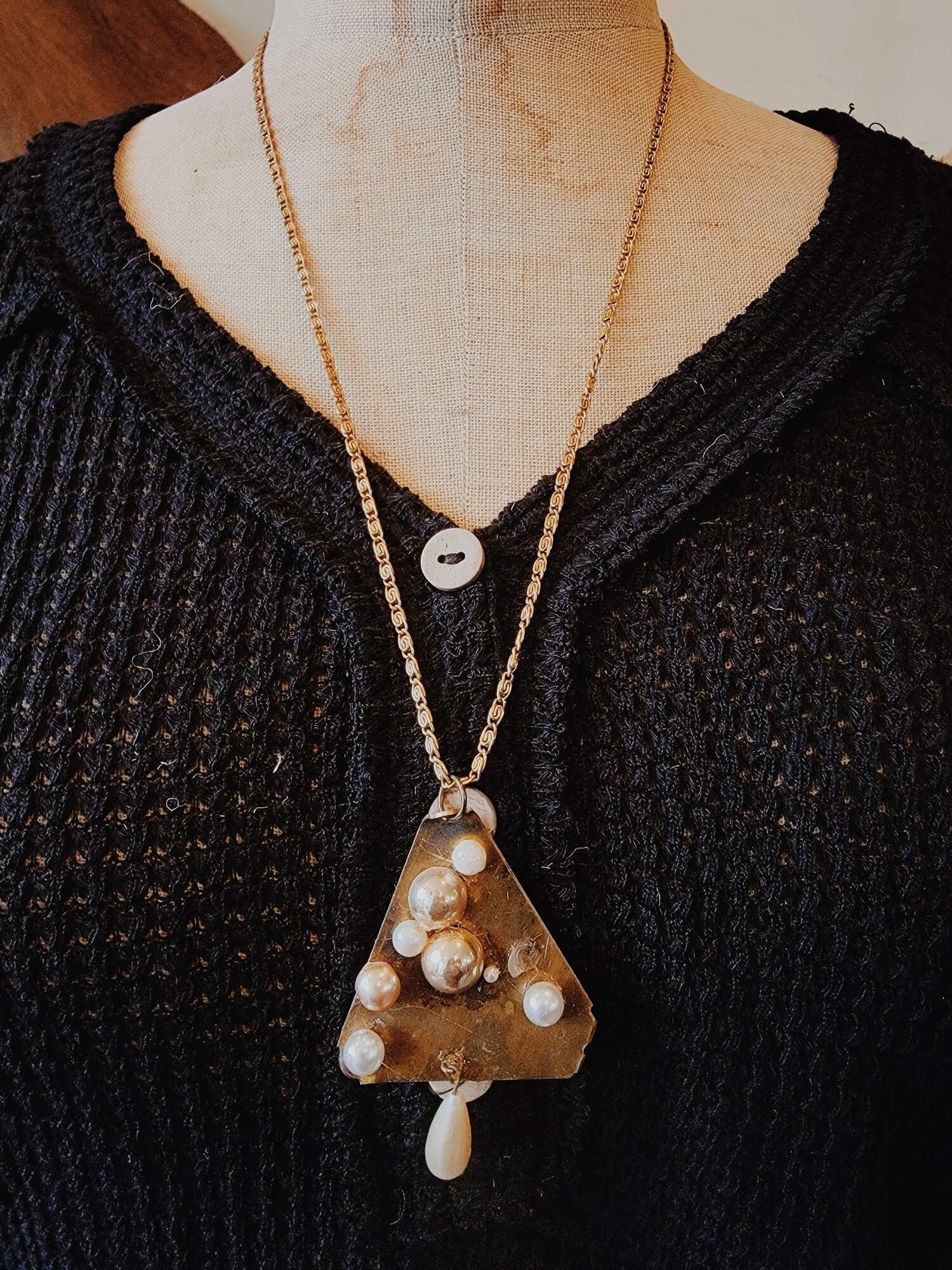 This handmade necklace has an antique brass triangle as its pendant with an assortment of faux pearls! It is on a 26 inch chain.