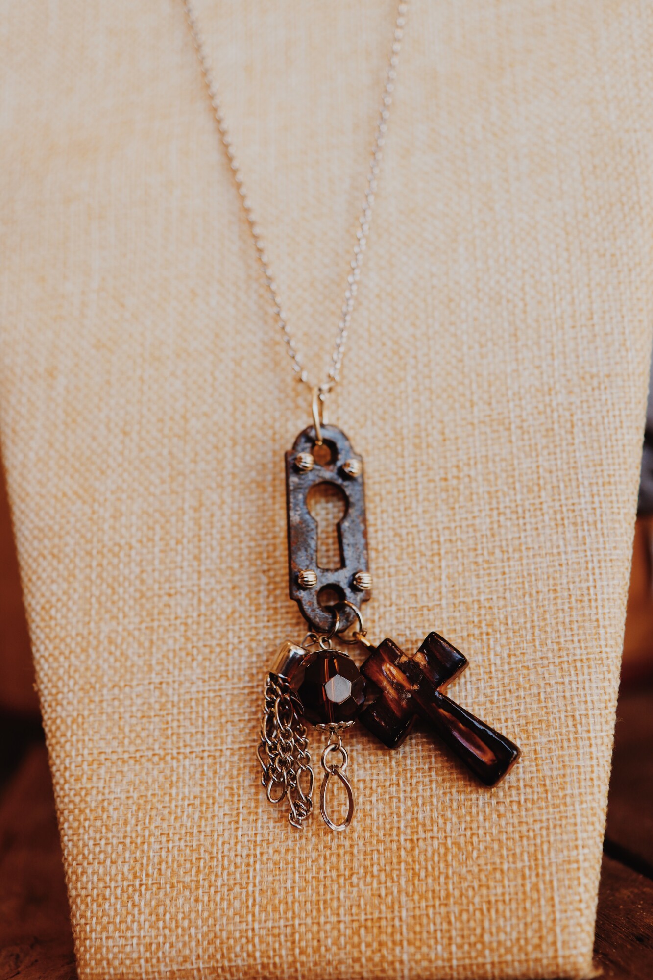 This necklace from Kelli Hawk Designs was handmade from vintage pieces! The pendant includes a vintage keyhole, a cross, an amber bead, and a chain tassel.  This hangs on an 18 inch chain.