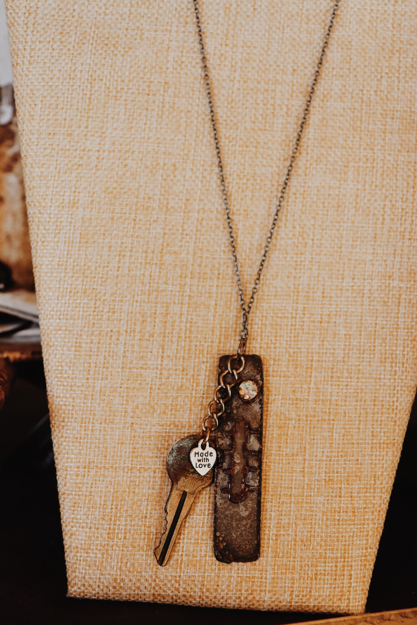 This necklace from Kelli Hawk Designs was handmade from vintage pieces! The centerpiece features two vintage metal pieces, one of which is an old key with a made with love tag attached. This hangs on a 20 inch chain.