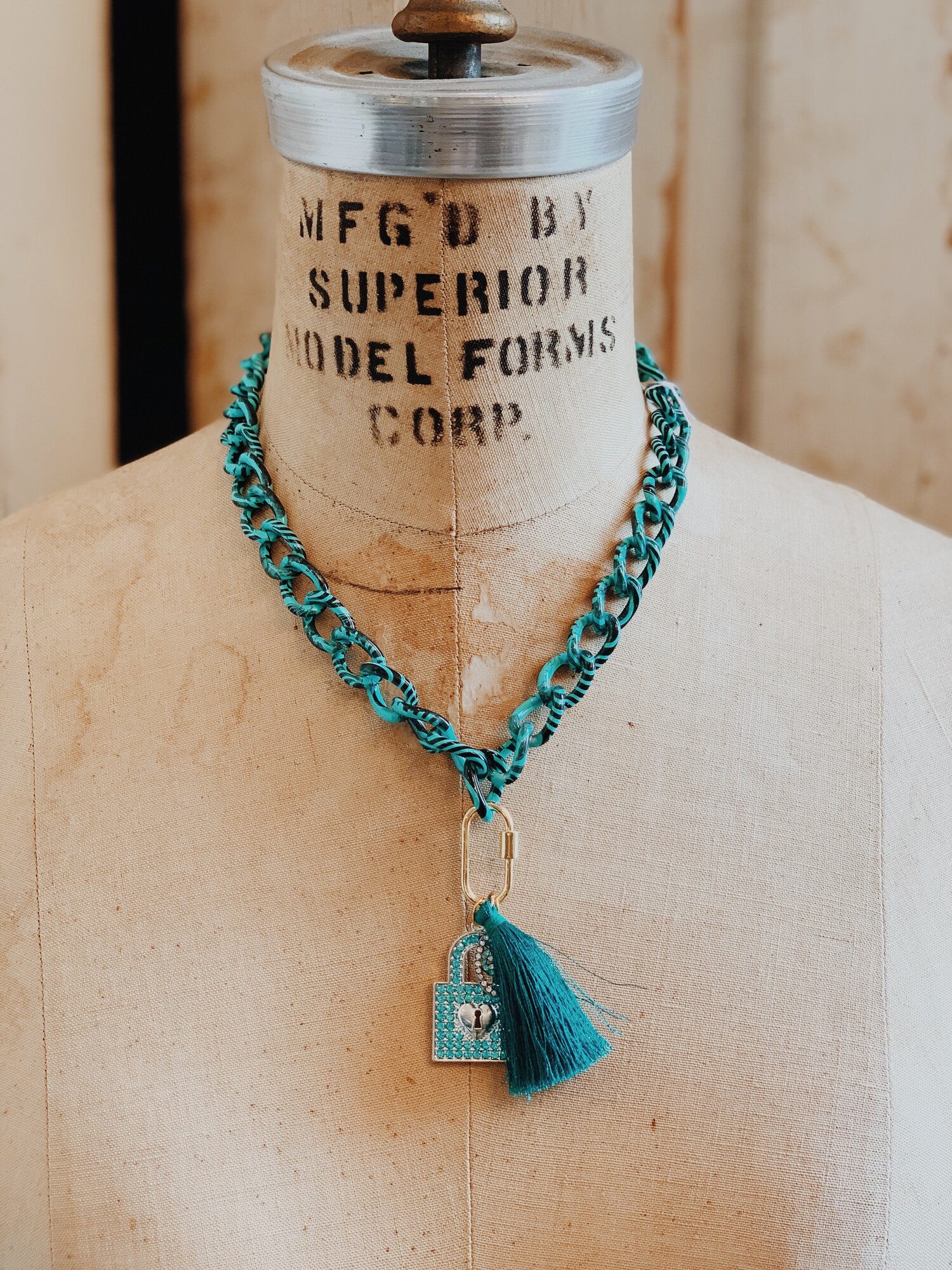 This Kelli Hawk Designs necklace is so fun and makes a statement! It is on a 17 inch turquoise and black chain with a 3 inch extender. A teal tassel and blue rhinestoned lock hang from this chain.