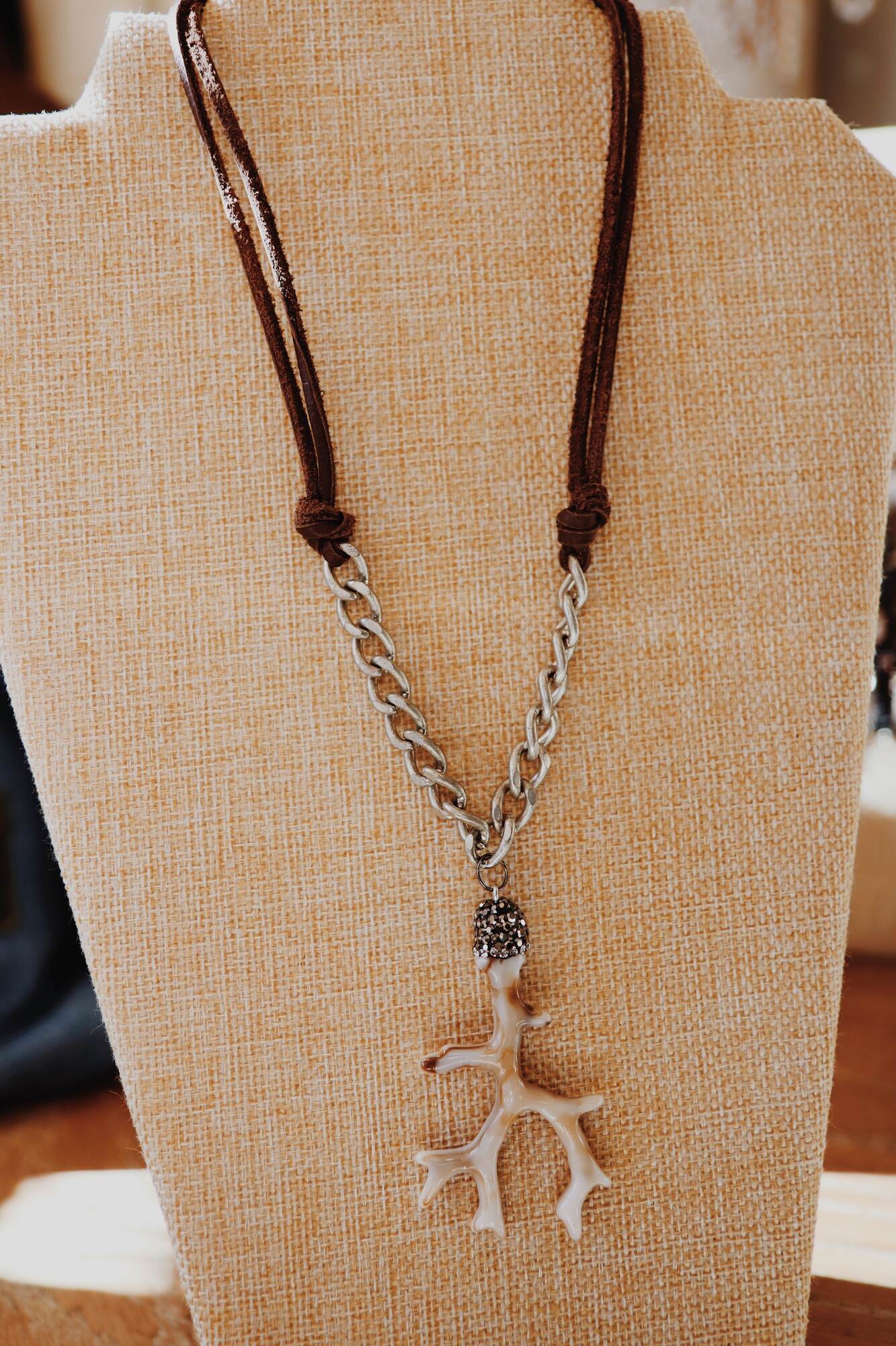 This handmade Kelli Hawk Designs necklace is on an 18 inch chain that transitions from leather cording to a silver chunky chain. The pendant is an adorable little antler!