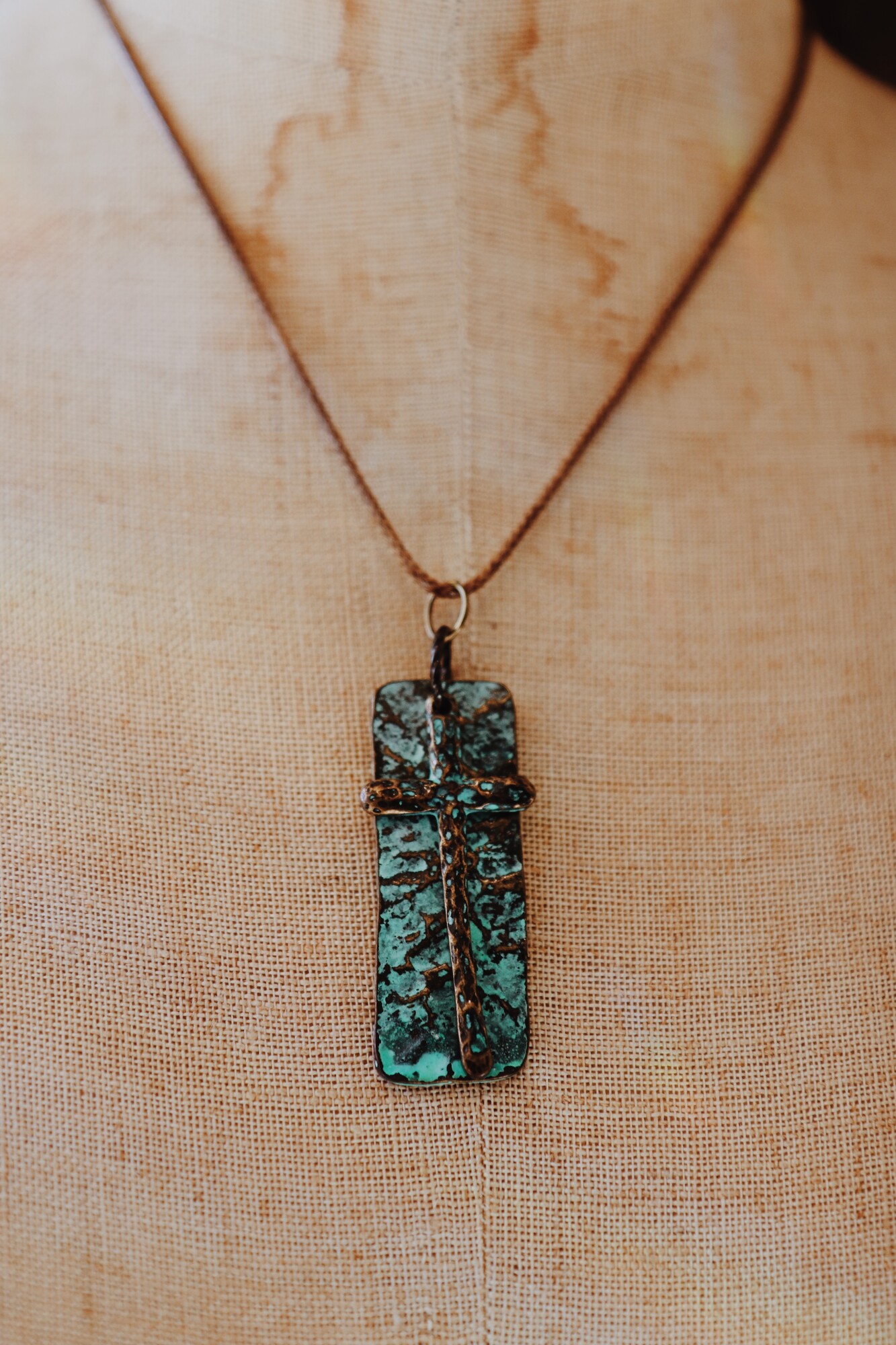 This Kelli Hawk Designs necklace is on a 17 inch cord with a 2 inch extender. The penant is a rustic teal metal plate with a cross infront of it!