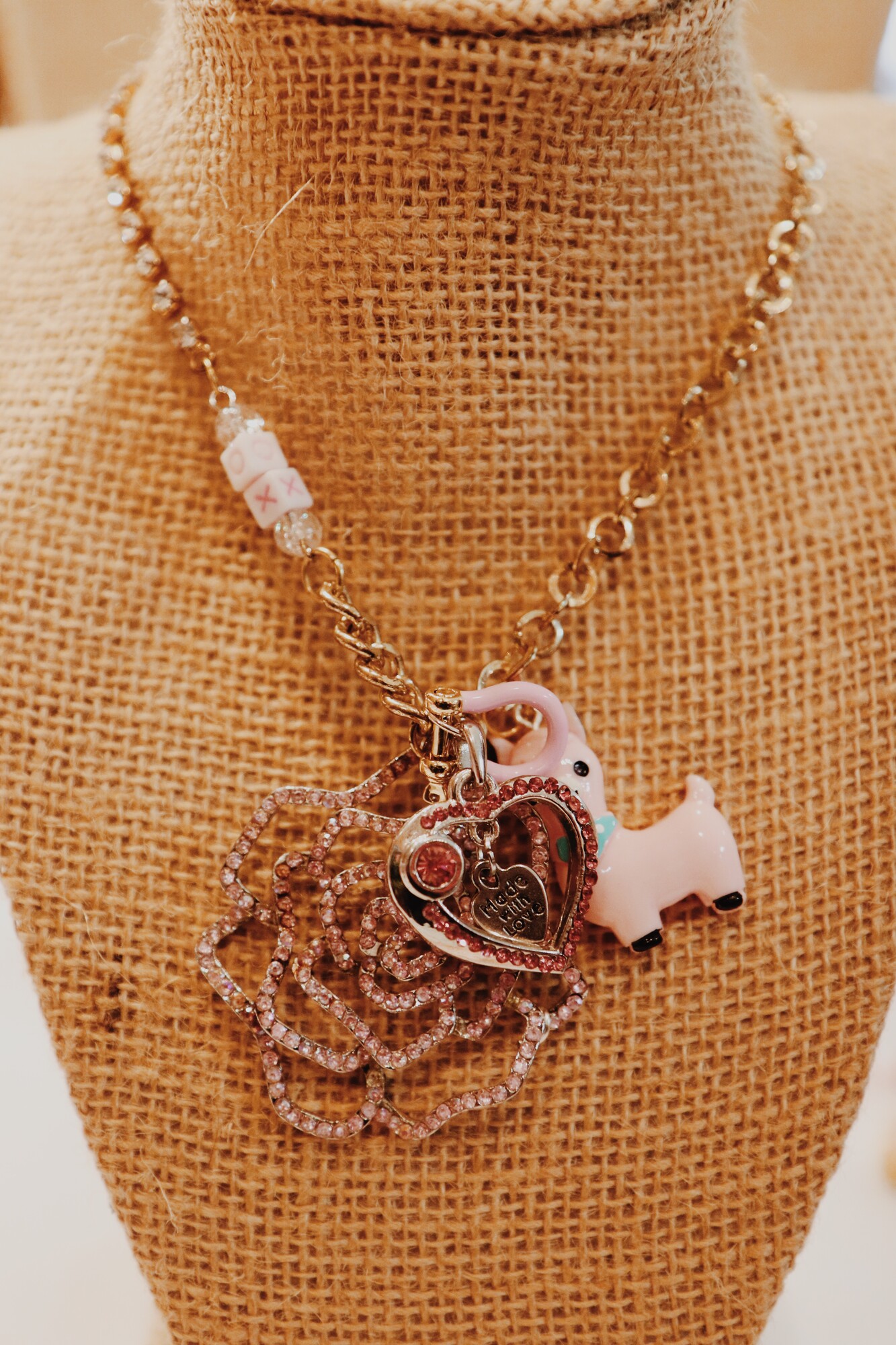 This handmade necklace by Kelli Hawk Designs is on a 20 inch mix matched chain with an XO on it! The centerpiece is a mix of charms that include a vintage flower, a pink llama, and a pink heart.