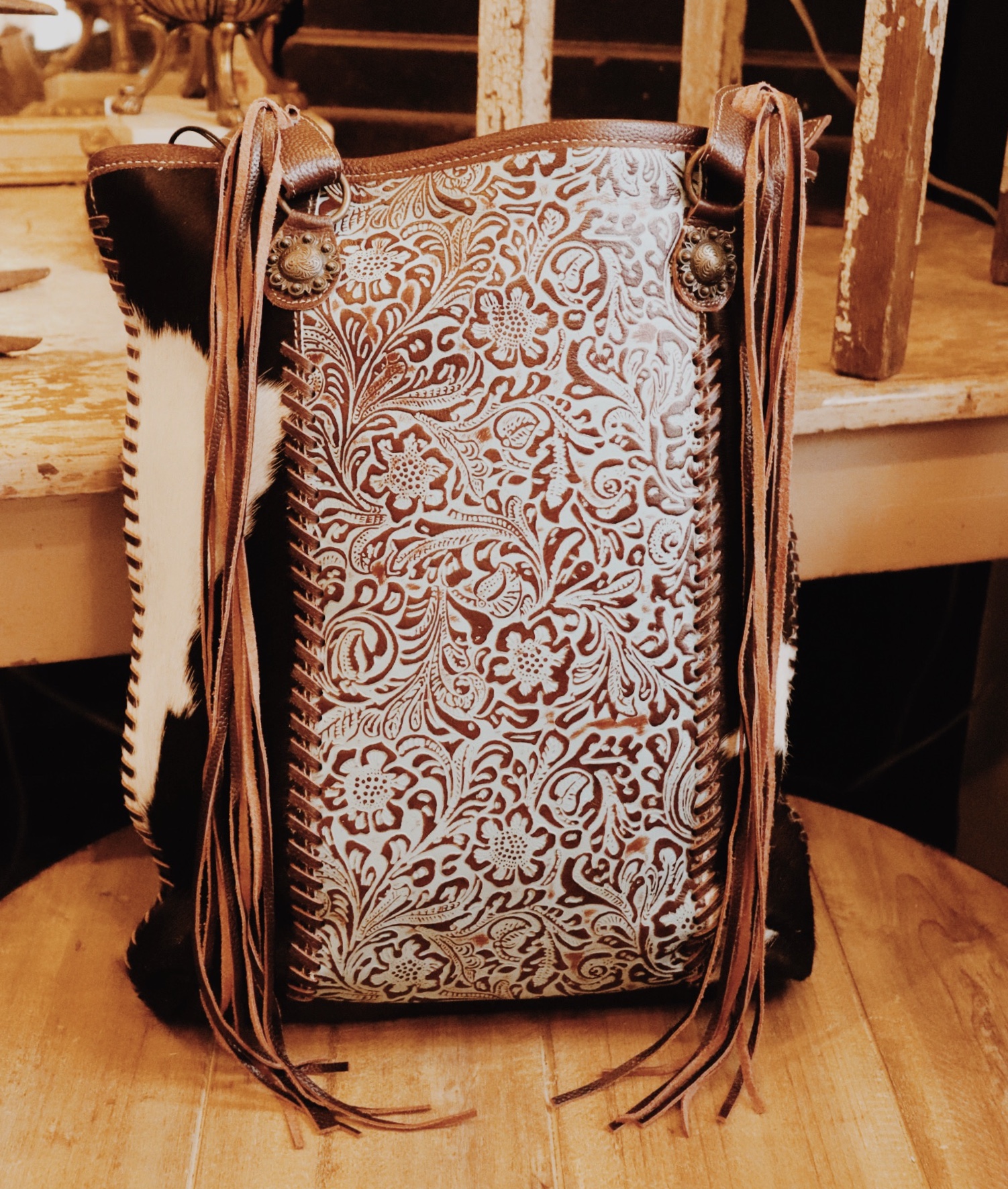 This Myra brand bag measures 15 inches long by 15 inches wide and is adorned by turquoise tooled leather, cowhide, and fringe! This bag has plenty of pockets for storage.