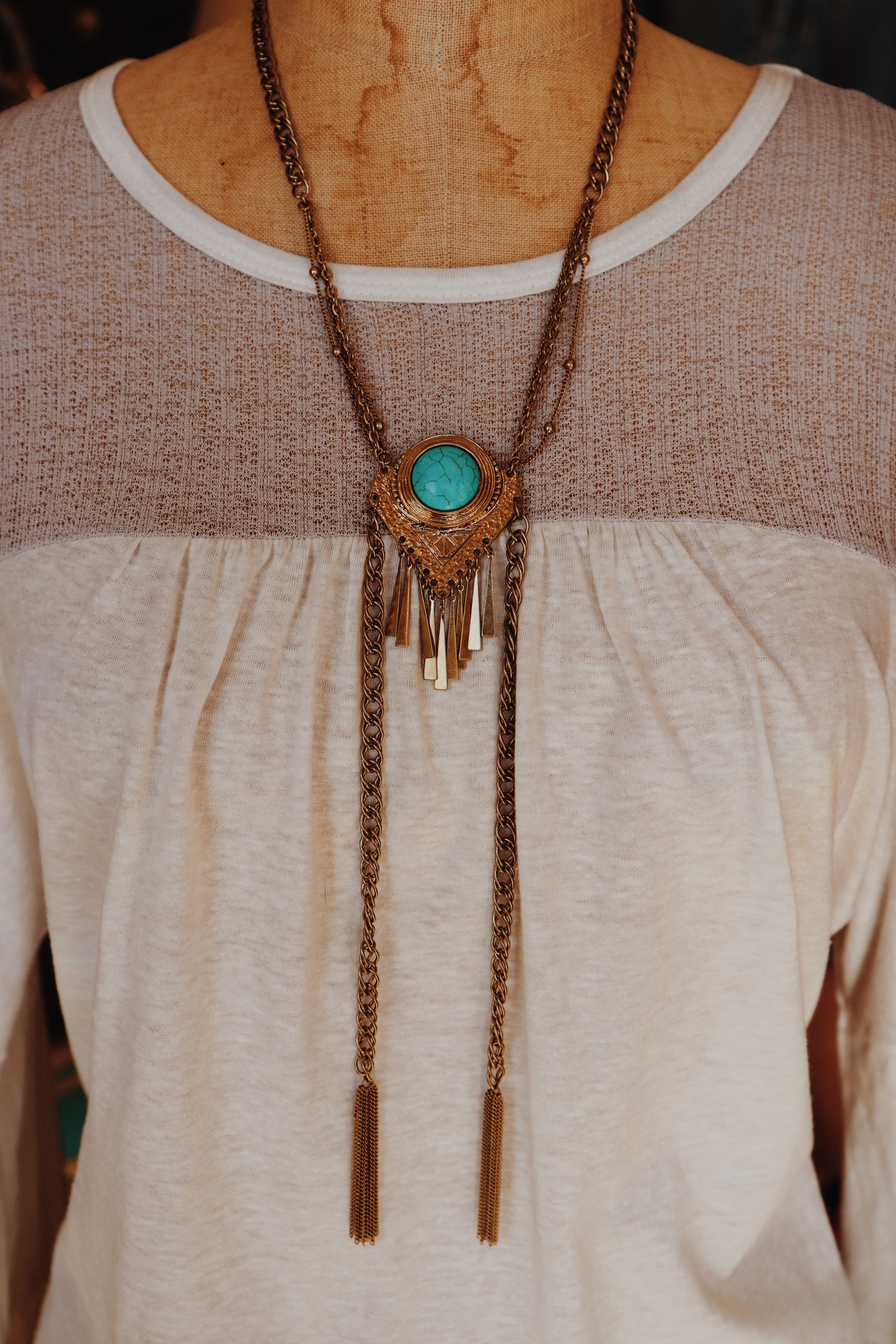 This unique beauty is the perfect gold colored piece! It is on a 21 inch chain with a 3 inch extender and has 9 inch tassel chains hanging from the turquoise pendant!