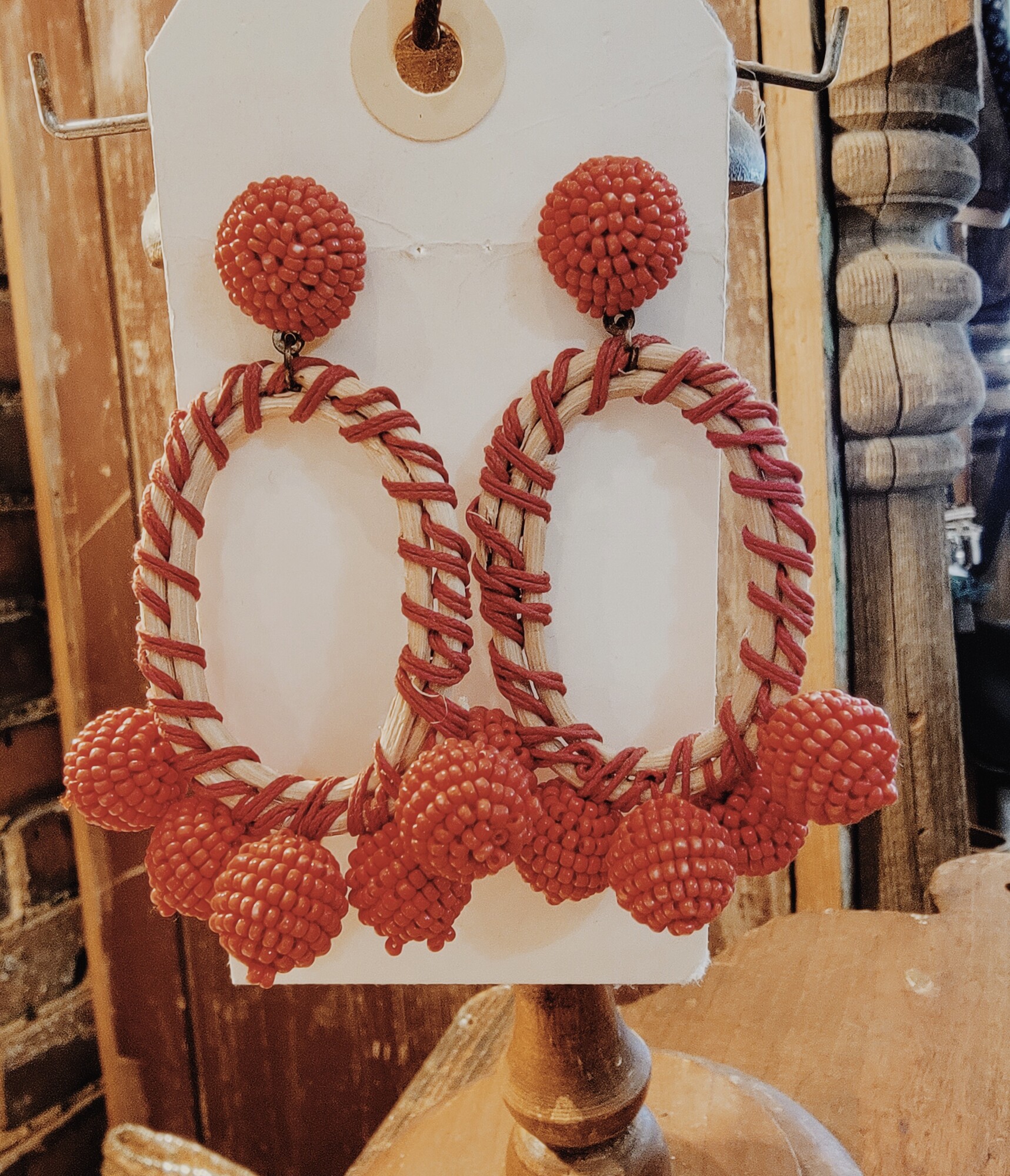 These earrings are in an oval shape with red thread wrapped around it. The post is small red beading. with five red beaded balls on the bottom. They are medium weight. 3 1/2 long.