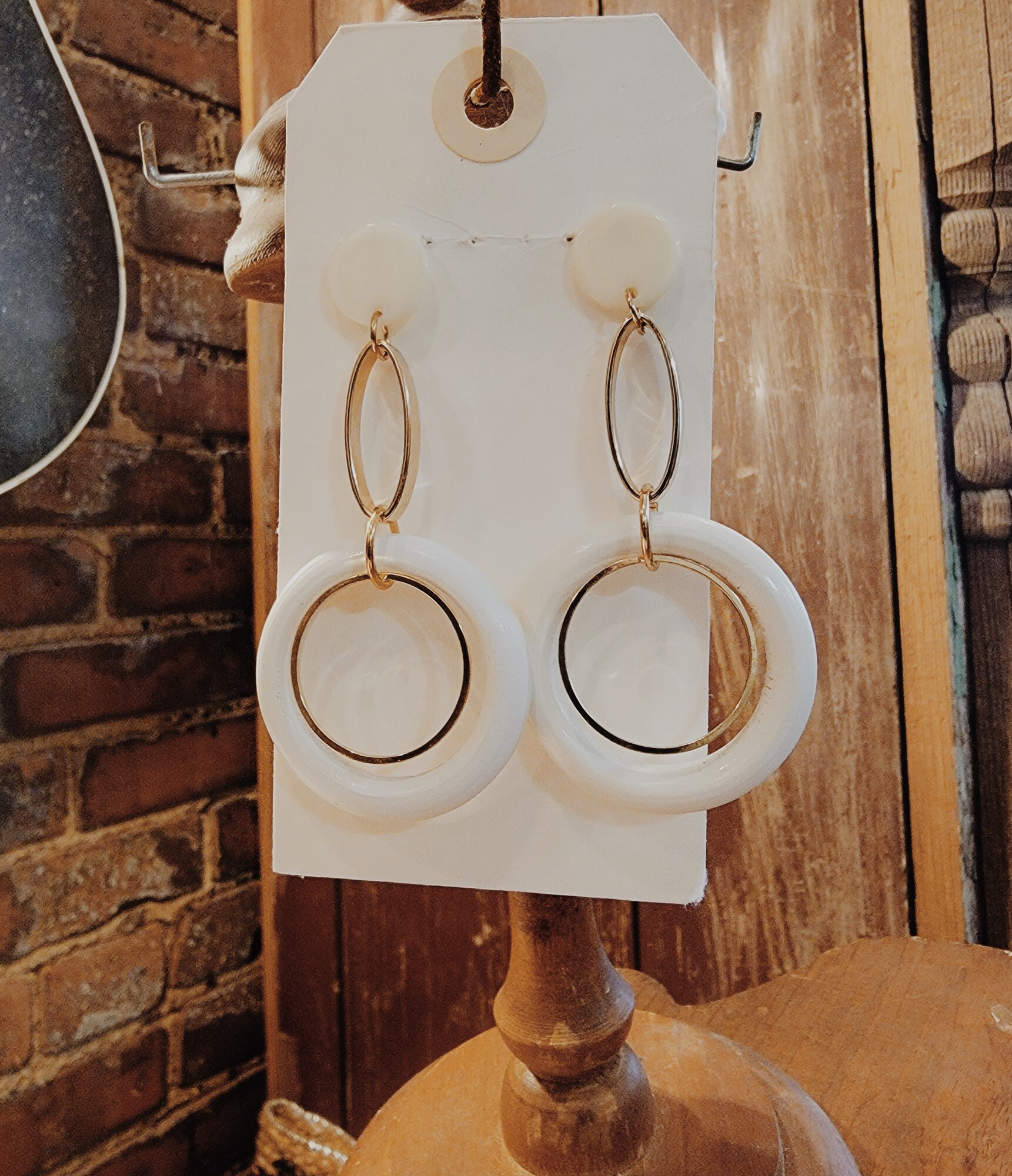These earrings are simple but cute. They have a cream button at post that is connected with a gold oval ring and that is connected by a cream circle with a smaller gold circle. These are light weight. 3 long.