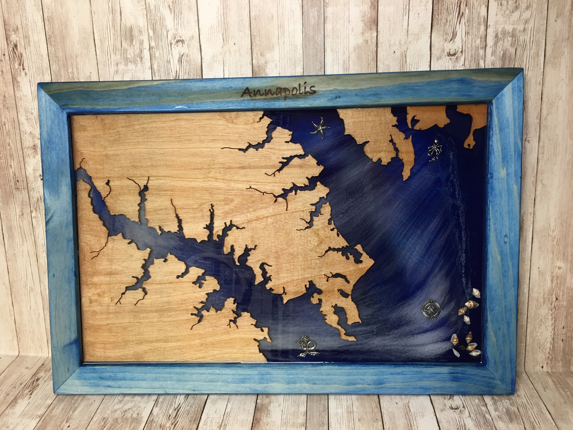 Annapolis Map
2203
Size: 14x21

This decorative map of Annapolis, Maryland was created with hand cut reclaimed wood and epoxy resin - no laser or CNC used. Each piece is unique. The frame is white pine and has marks from the wood's previous
life. The map is reclaimed maple. The epoxy resin used is non-toxic, food-safe and no-VOC.

When choosing products for your home that contain resin please know what you are buying. The epoxy resin we use is much more expensive because it is non-toxic. It is formulated using the highest quality materials and therefore produces no VOCs or fumes. It is a clean system, meaning there are no solvents or non-reactive diluents-everything in it reacts so nothing is free to become airborne and cause health issues. Our resin is so safe it can be safely used as a food contact surface.