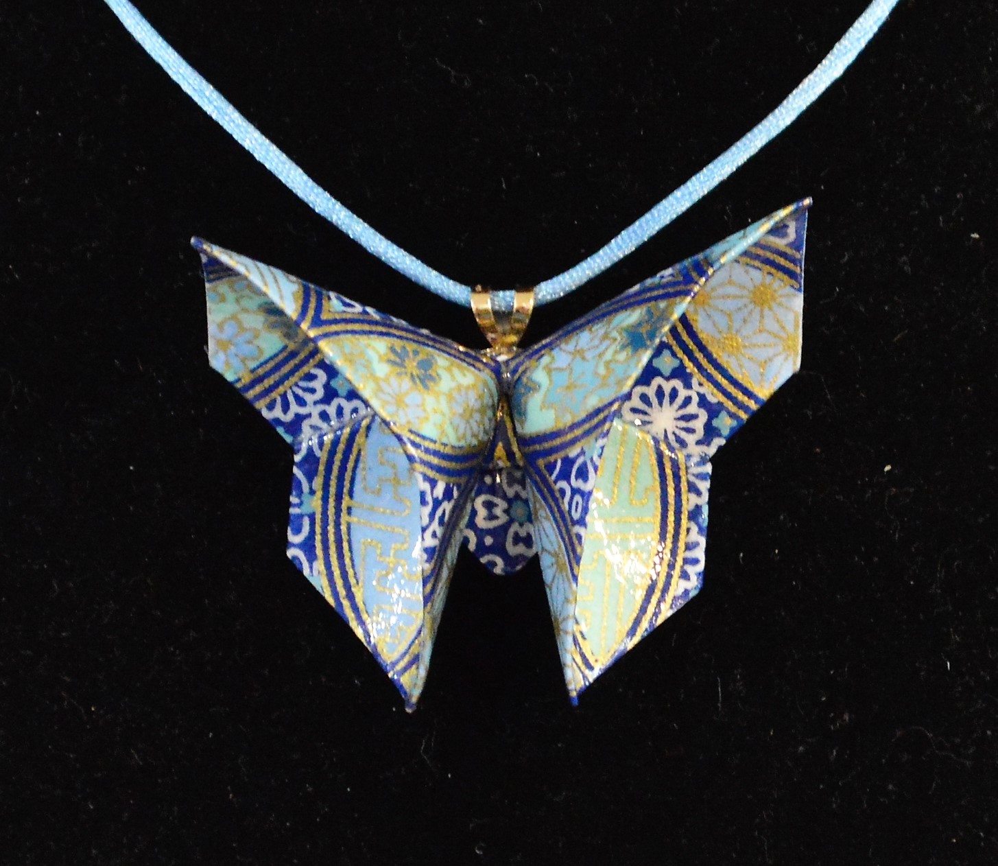 Rich Gray
Blue Origami Butterfly Necklace
Paper  2 x 2.5 inches
Origami butterfly folded from paper with shades of blue and gold highlights.  Coated with clear acrylic sealants for durability and hung on an 18 inch blue cord.