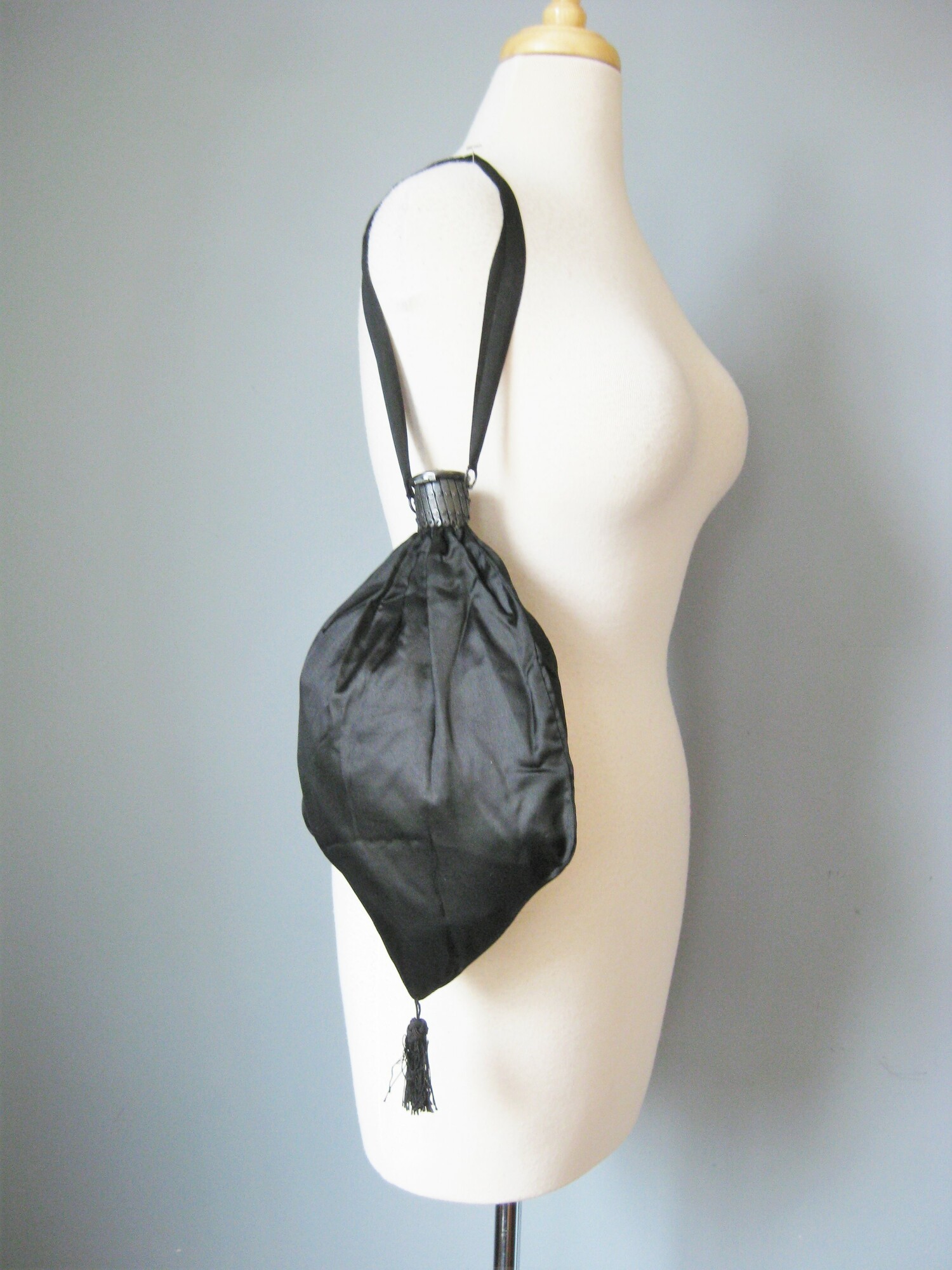Very old silk purse, probably used as part of a Victorian or Edwardian mourning ensemble.
This back is black with black satin ribbons and a metal expanding frame.
The frame is topped with an open work metal cap with rhinestones.
It has a dangling tassel at the bottom.
The frame opens to reveal a dark lavender silk lining.
Handmade.

Amazing condition! no flaws

10 wide at its widest point
13 long/tall
8 long
12 around

thanks for looking!
#47337