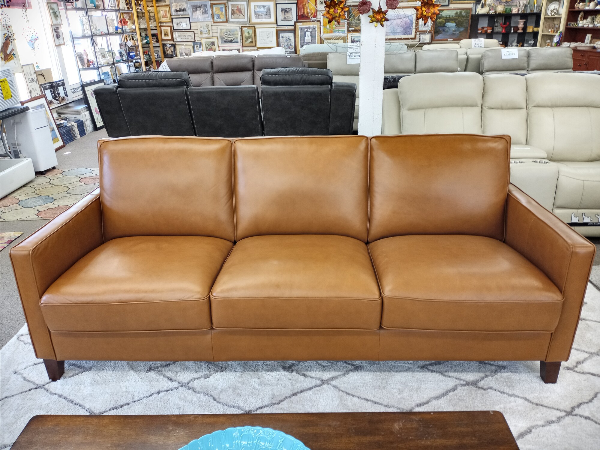 Cognac Nice Leather Sofa
    Color: Cognac Brown or Taupe Tan
    Top Grain Leather on all seating areas and arms rests with split grain leather on the front rail, sides and back
    Kiln-dried solid wood frame
    L-braced hardwood frames and glued corners
    Removable seat cushions composed of 2.25 lbs density foam core.  Cushions are double-wrapped with down feathers.
    No-sag spring platform to ensure support and comfort
    Back cushions feature bagged and channeled polyester fiber to maintain its shape
    Back cushions are not removable
    Padded outside arms and backs
    Solid wood legs in Dark Brown finish 5” H
    Leather care: Position your leather furniture away from direct sunlight, high-wattage lights, heating and air conditioning registers. These remove necessary moisture from leather that may cause cracks or splits. Gently wipe your leather once a week with a clean dry or slightly damp soft cloth to avoid build-up of dirt and dust. Avoid using chemical cleaners which are harmful. Clean up spills immediately using a soft cloth. Dab with a slightly damp cloth and dry the area immediately with a clean white towel.
    Seat cushion depth is 22”
    Seat cushions are 9” thick
    Seat height dimensions are 26”W x 20”H
    Arm height is 25.5”
    Arm width is 4”

Sofa Dimensions:

    85.5” W x 38” D x 35” H