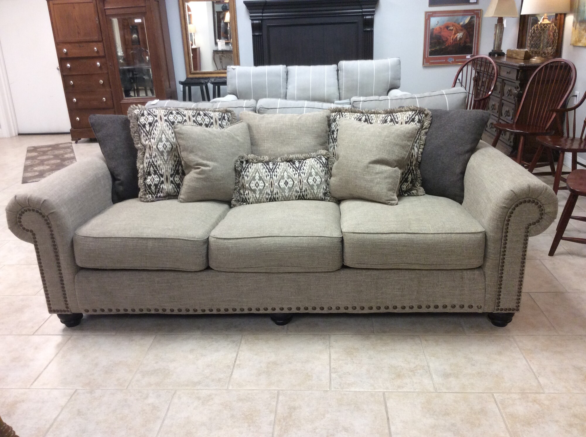 This is a Beautiful Cream Tweed 3 Seater Sofa from Ashley. This Sofa has Nailhead Trim around the arms and Dark Brown Circled Feet. This Sofa also features 8 pillows that come with the Sofa; 2 Brown, 3 Cream and 3 Patterned.