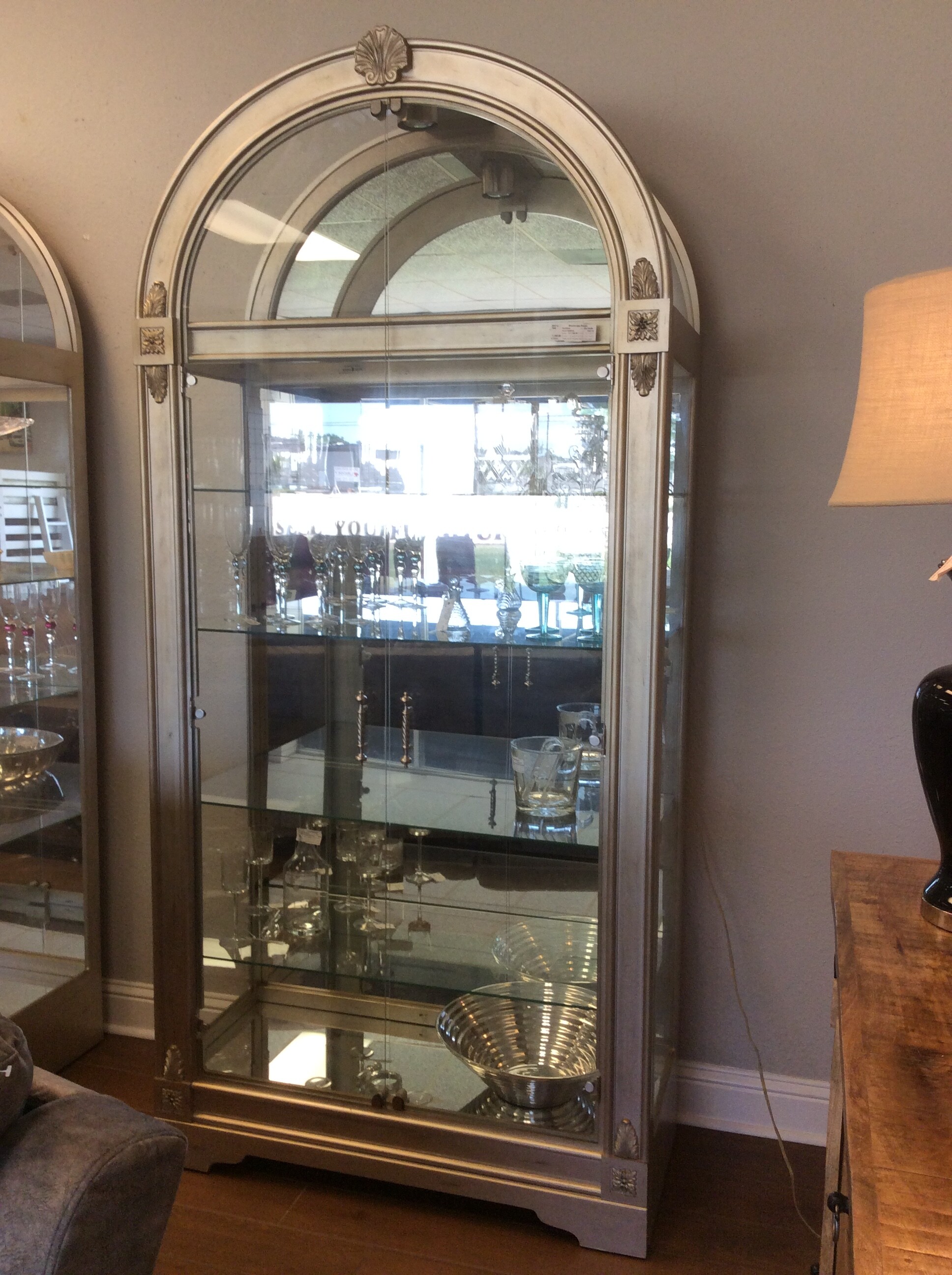 This is a beautiful Howard Millar Silver & Glass Curio Cabinet. This Curio has Double Glass Doors with Silver Handles, Mirrored Back and Bottom, 1 Light and 5 Adjustable Shelfs.