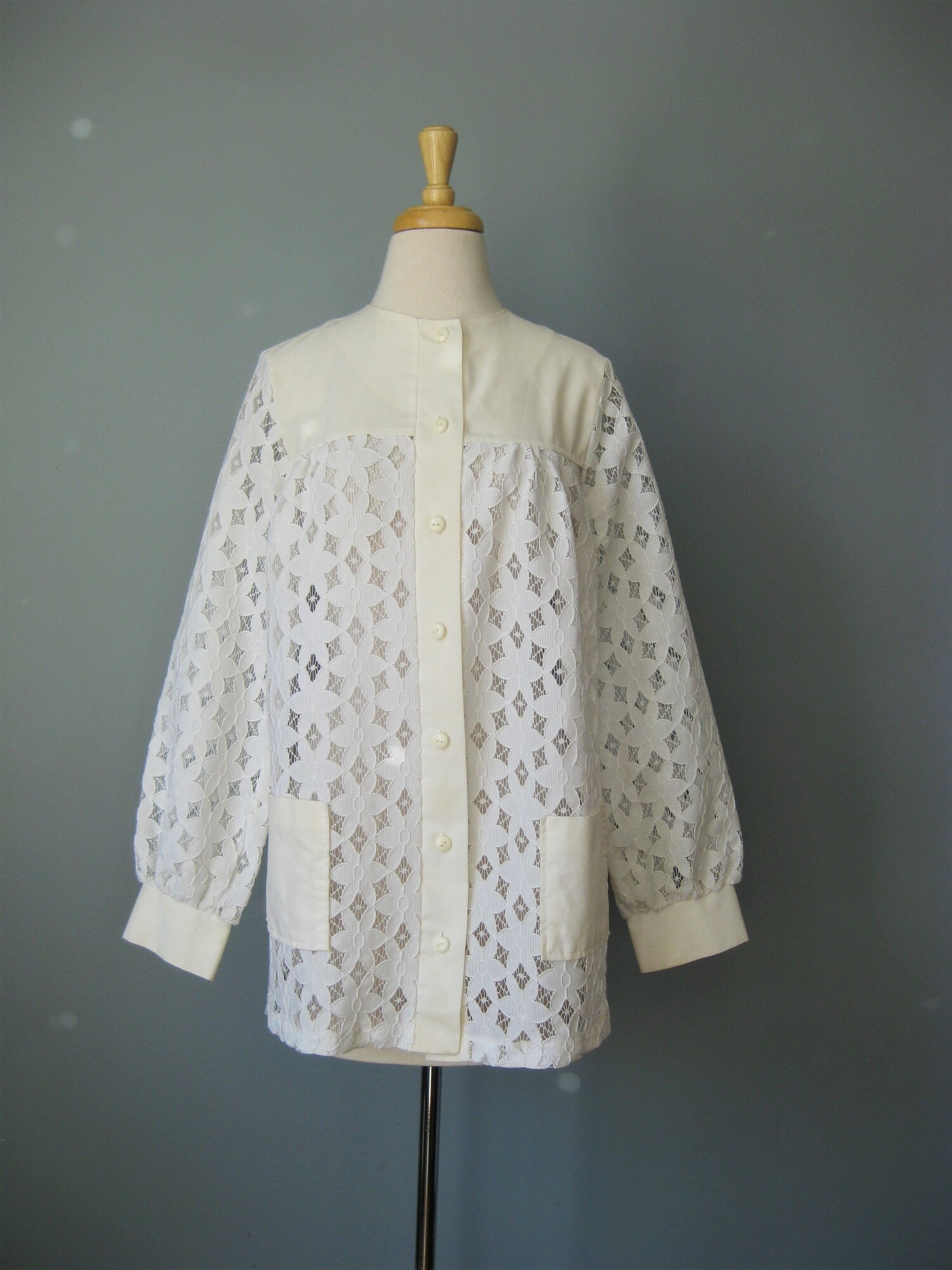 This white lace blouse from the 1960s is so feminine.
It might even be a maternity top with it's swingy shape.
The front and sleeves are unlined lace
the yoke and cuffs are a thin cotton or cotton poly blend.
the lace is bright white but the yoke and cuffs have mellowed to an offwhite color.
Otherwisse in perfect condition
Buttons down the front and on the cuffs
No tags
Here are the flat measurements:
shoulder to shoulder: 14 3/4
armpit to armipt: 21 1/2
width at hem: 24
Length from neck to hem: 28 3/4

thank you for looking.
#36606
