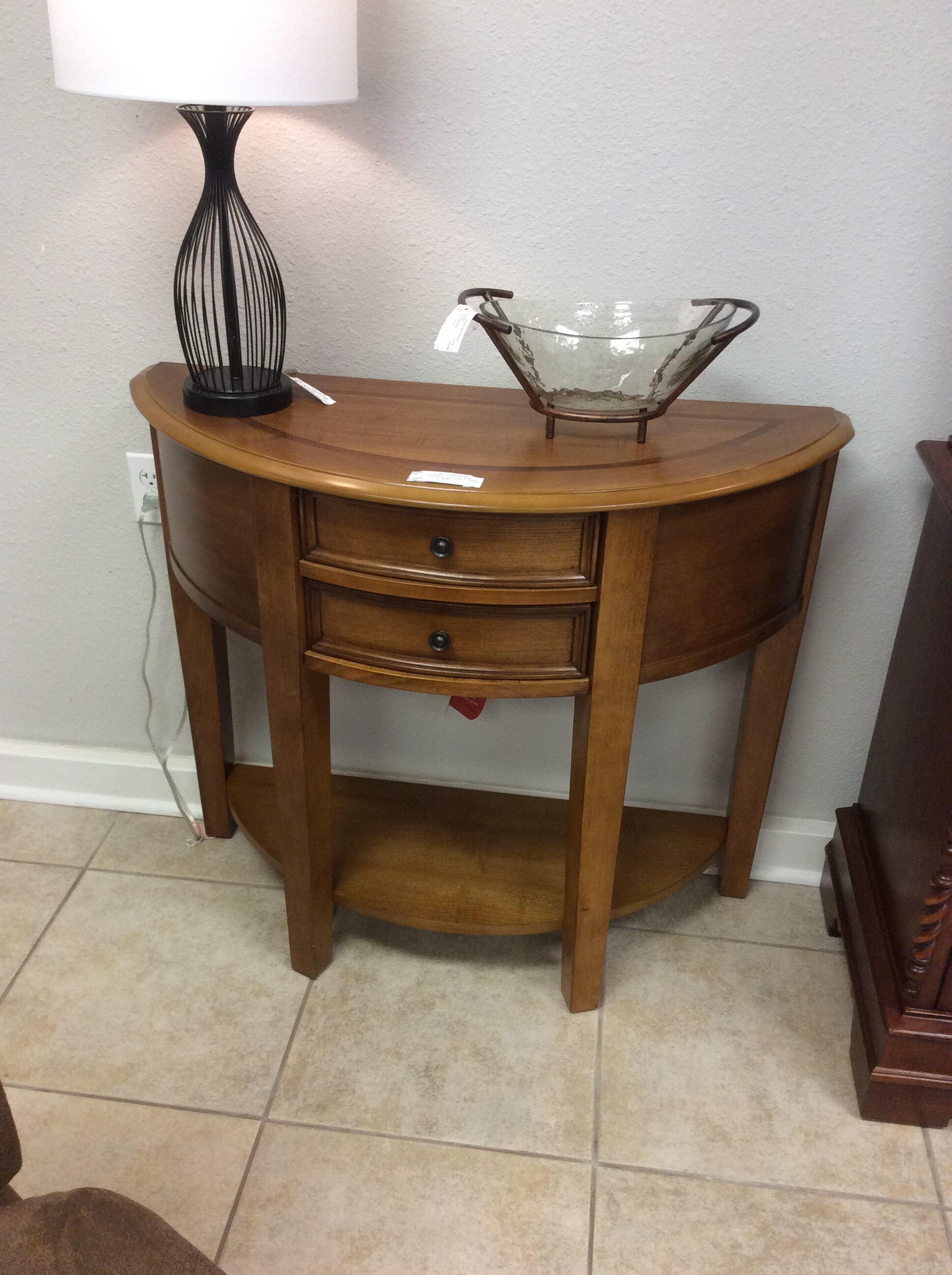 This 1/2 moon entry table has a medium wood finish and 2 center drawers,