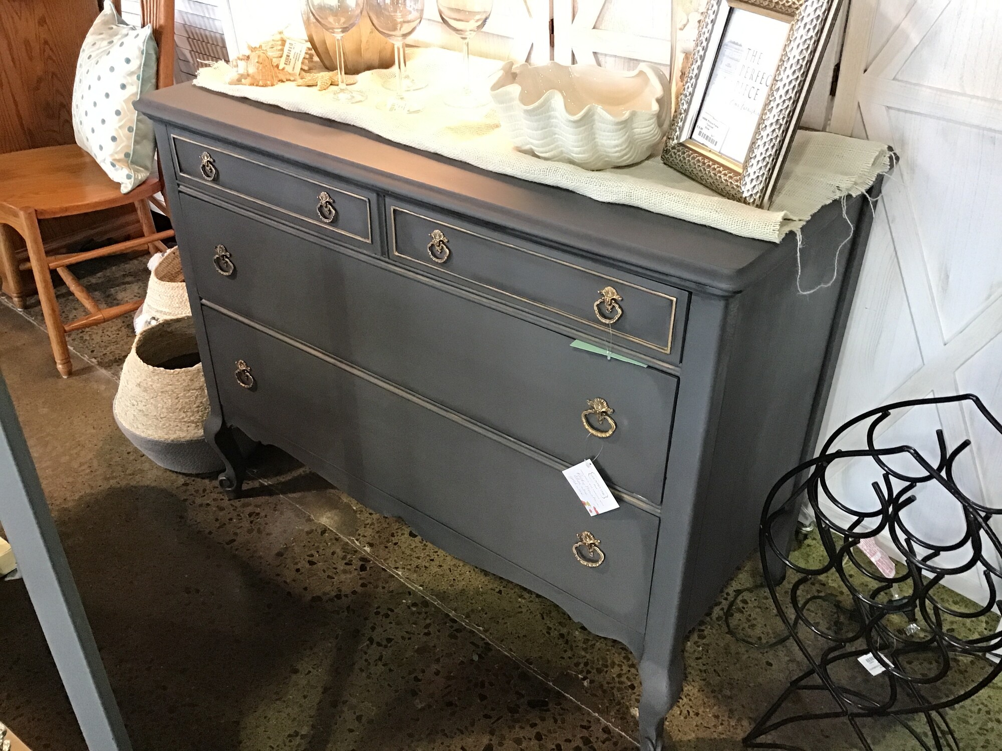 This beautifully updated vintage dresser was painted by one of our local artists using Country Chics Rocky Mountain paint. She used clear wax as a protectant and gold wax for highlights. The hardware was also updated to a gold finish. It has 4 drawers, which all move in and out smoothly. Great accent piece for any room!
Dimensions are 44 in x 22 in x 35 in