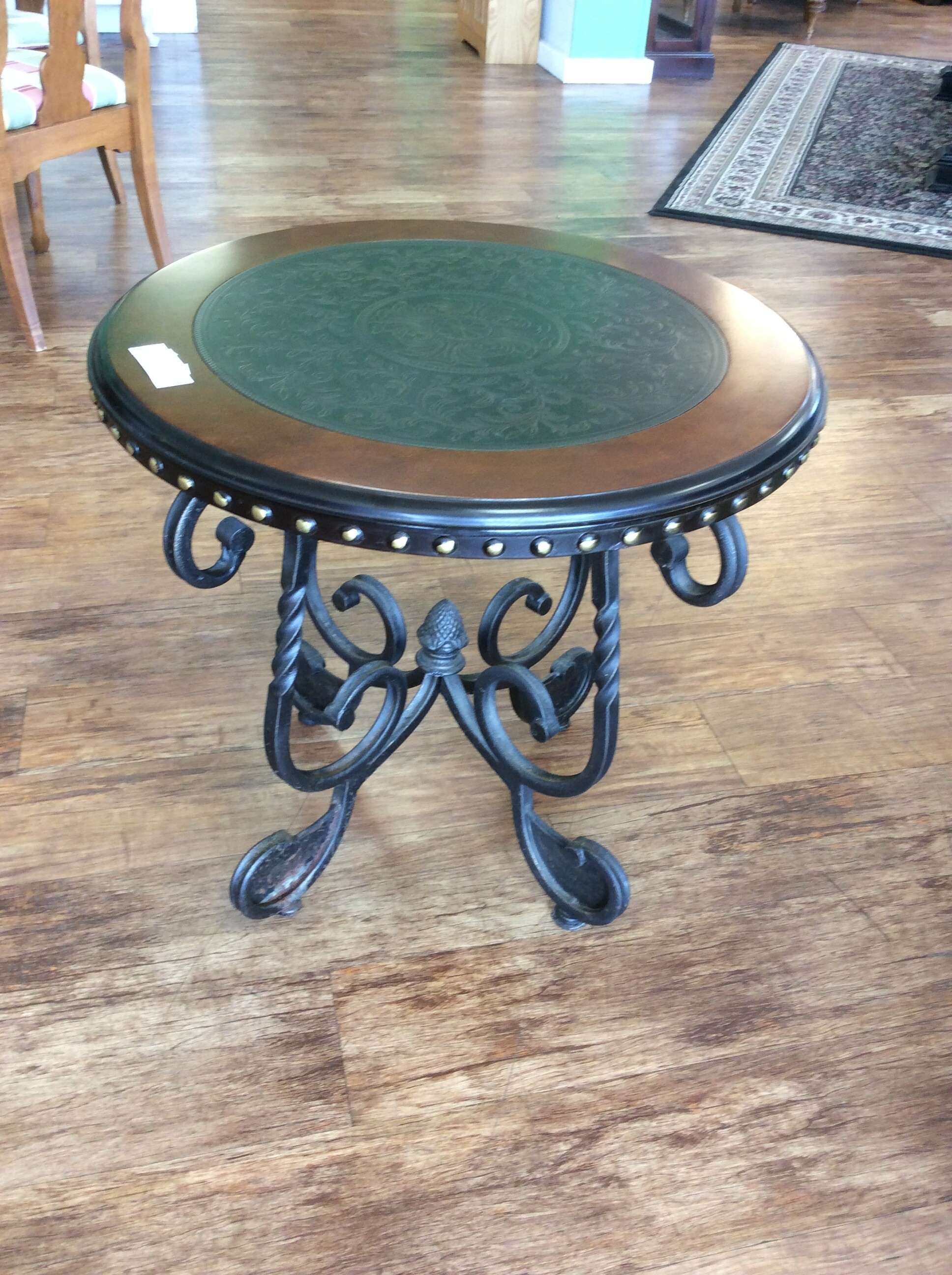 This round occasional table has a embossed metal insert with a wrought iron base.