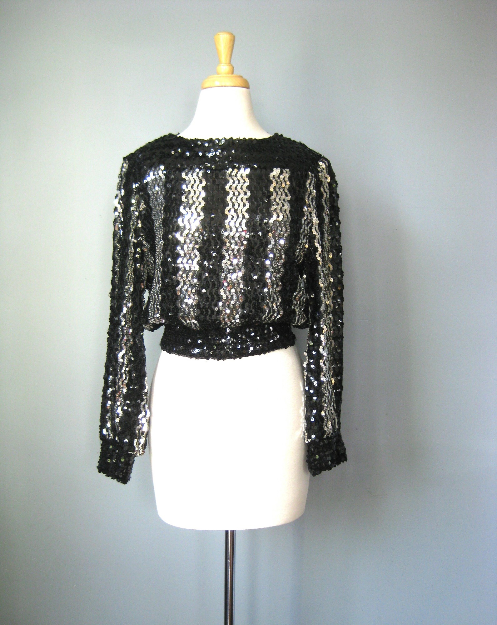 Vtg Caron Sequined Top, Black, Size: Medium
Fun sweater for evening.
Black and silver sequins arranged in wide vertical stripes on the front, back and sleeves.
It has a kind of baseball jacket/sweatshirt silhouetter, elasticized at cuffs and waist and somewhat cropped.
Squarish neckline
unlined
Quite stretchy overall, including the waistband but the cuffs have lost a good deal of their snap.
by Caron, cute label
Made in the USA

Flat measurements:
shoulder to shoulder: 16
armpit to armpit: 20 unstretched
waist: 13.75 stretches comfortably to 17
length: 20

Thanks for looking!
#43429