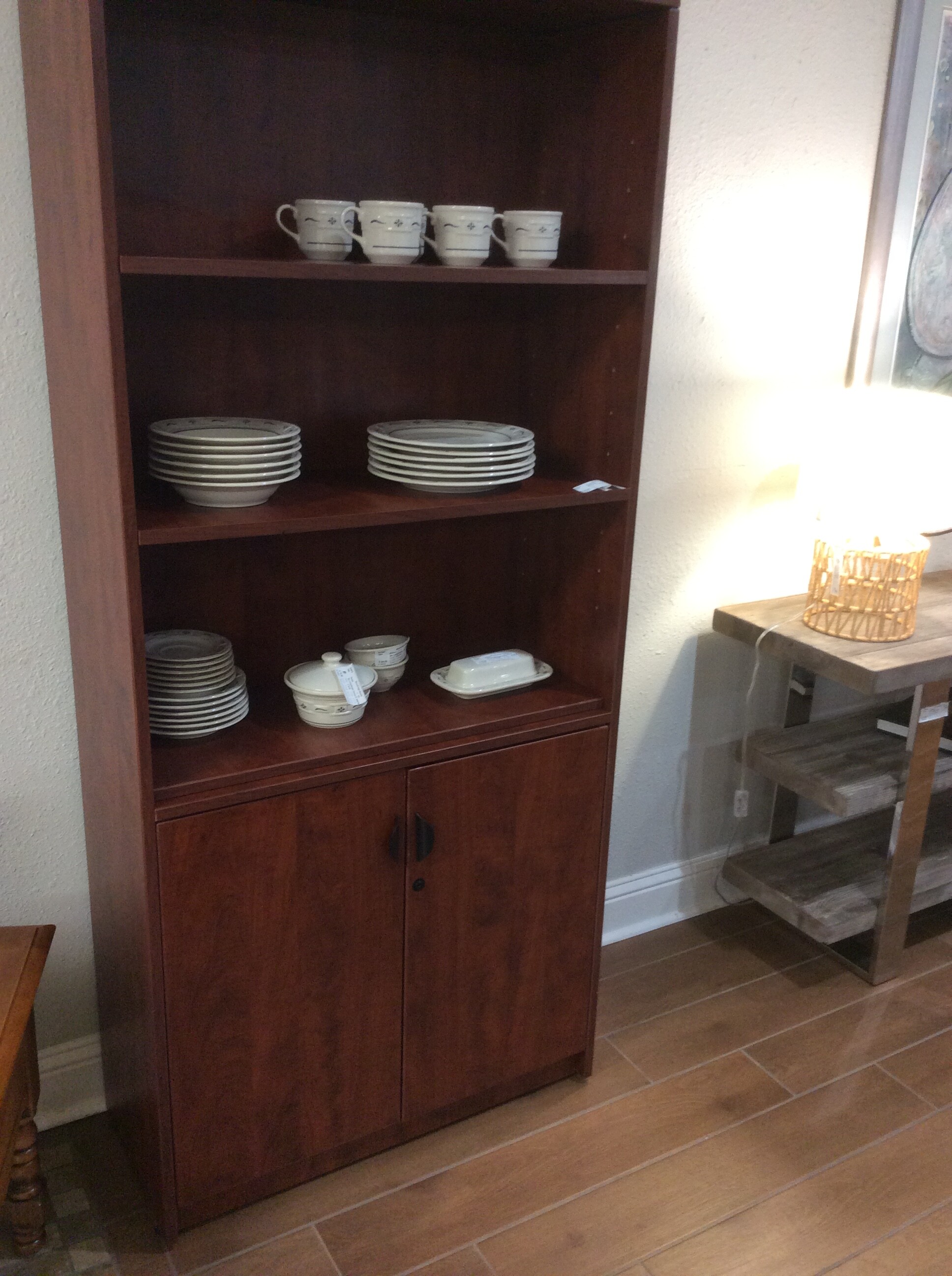 This bookcase has both open and closed storage and is done in a dark wood finish.