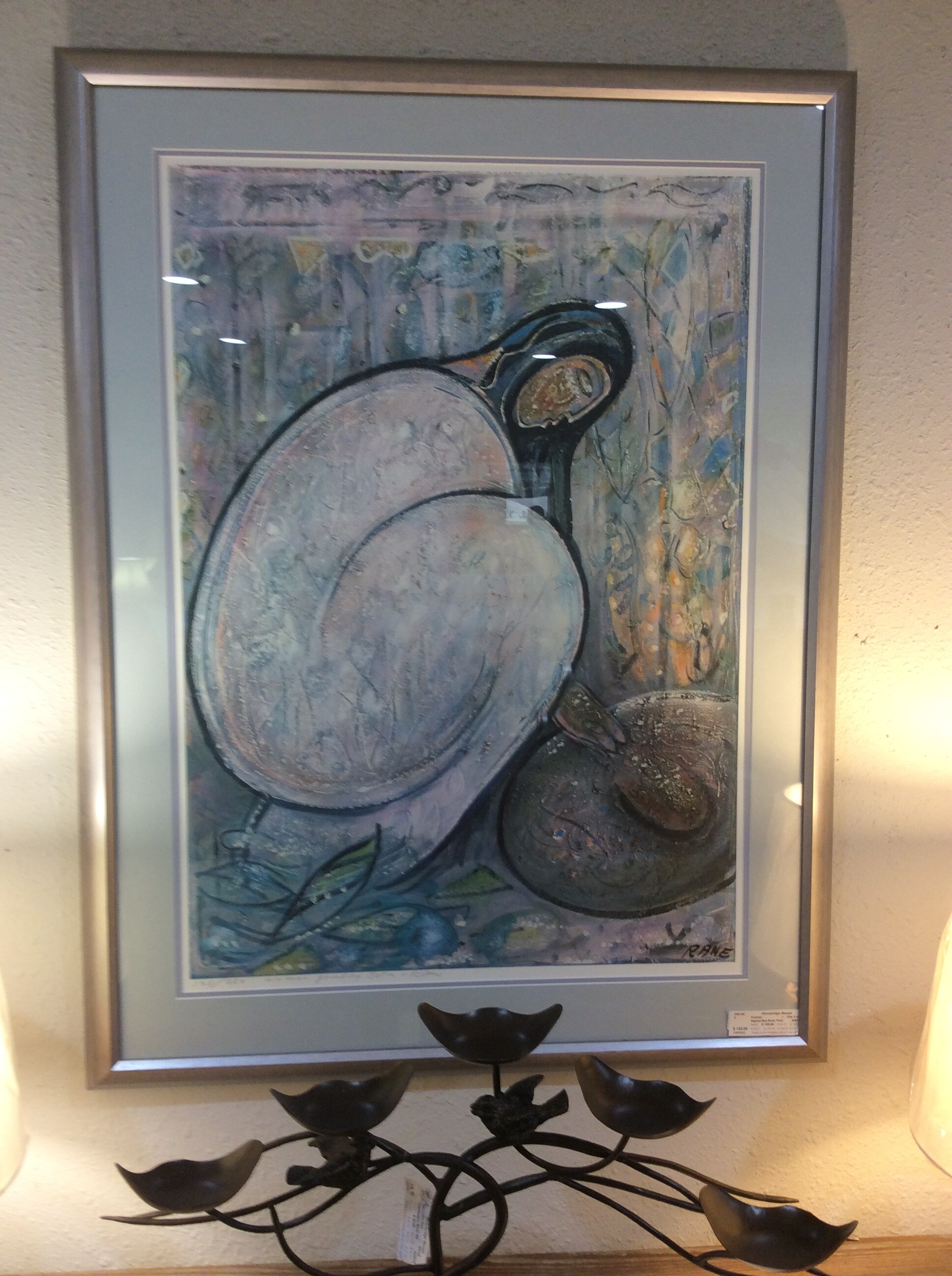 This is a signed and numbered Rane Print of a women grinding corn abstract. This print has a blue matting and silver frame.