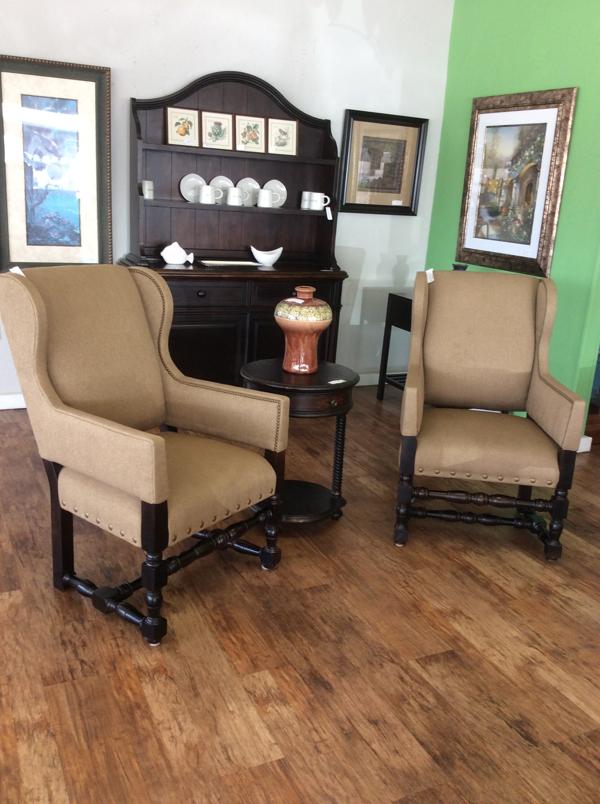 These are a tan pair of Lee Ind Wing Back Chairs. These chairs have a dark wood leg base and nailhead trim.