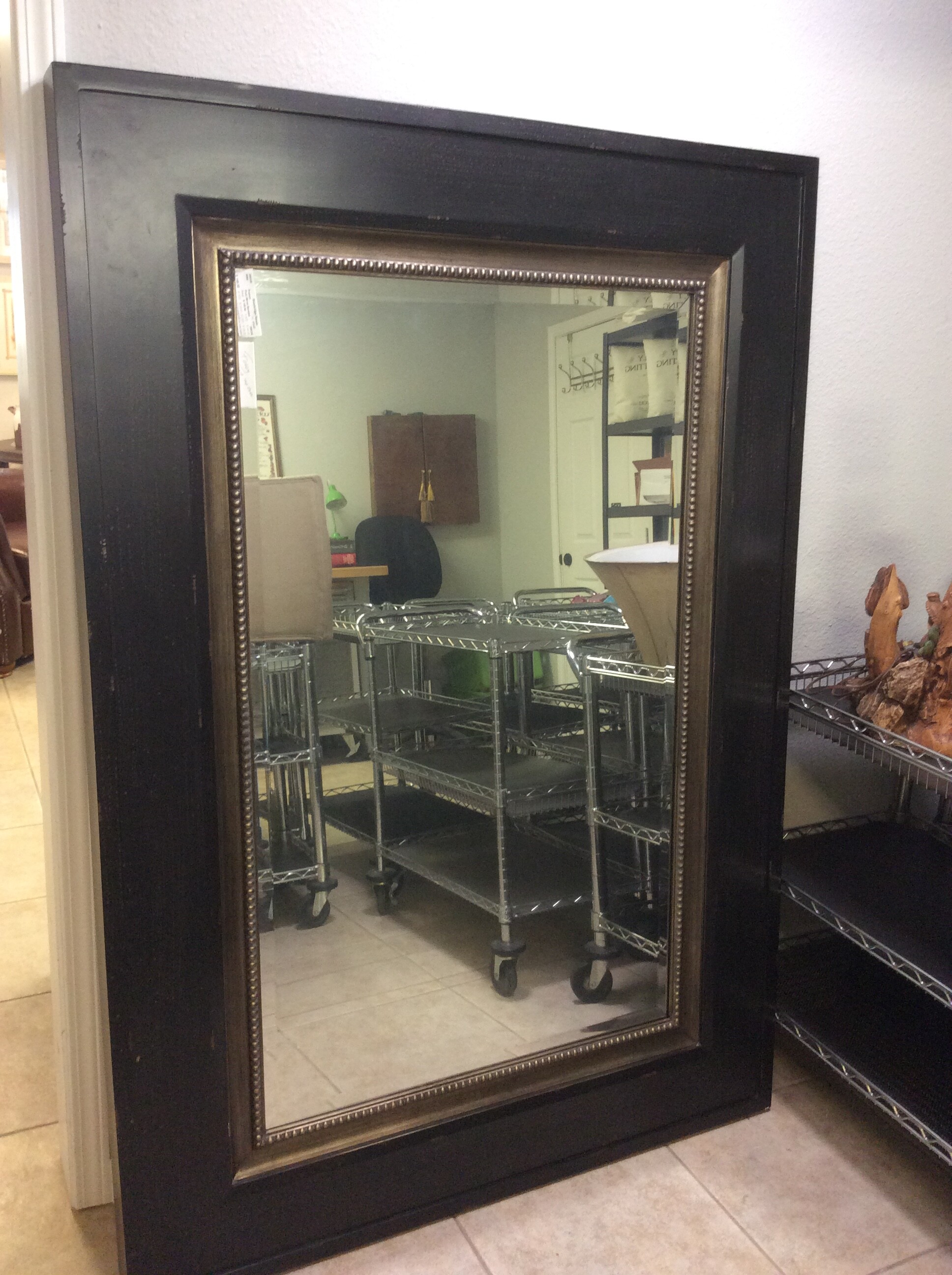 This is a large, dark brown, metal, beveled floor mirror.