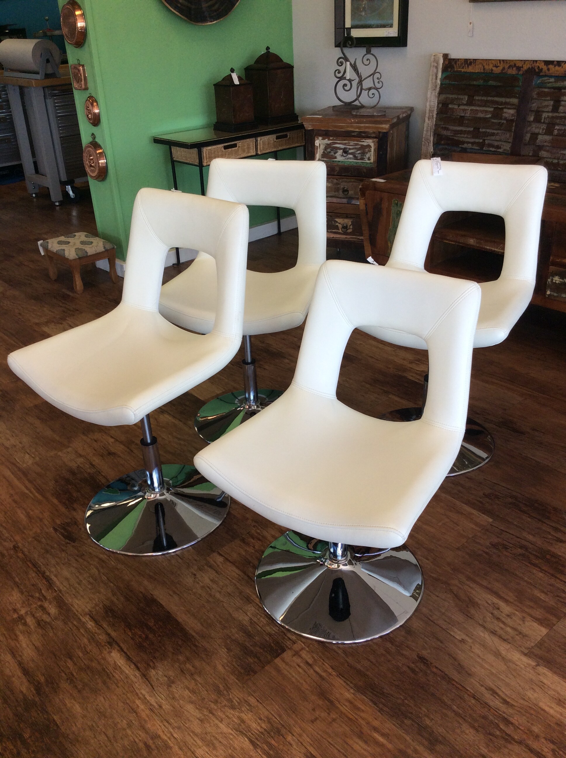 This is a set of 4, white leather, adjustable barstools with a chrome bottom.