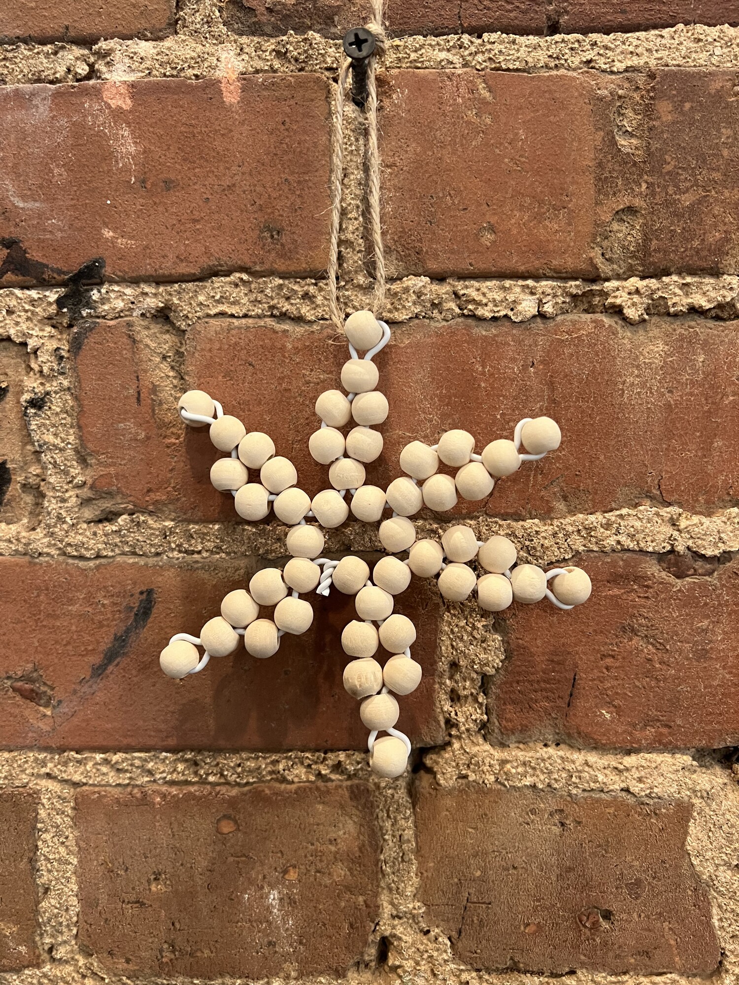 This Bead Snowflake Ornament adds a homemade feel to your tree or other winter decor. The beads are strung on a  white plastic coated wire wrapped into a pretty snowflake shape. They are topped with a jute hanger for easy hanging on your tree or hanging from garland
Measures 5 inches high and 4 inches wide