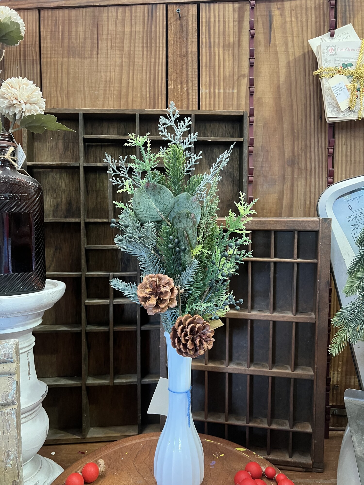 This lovely stem features a nice mixture of seasonal greenery, pine cones and berries. Stem is perfect to just drop in a vase for a wintery feel. Stem measures 20 inches tall