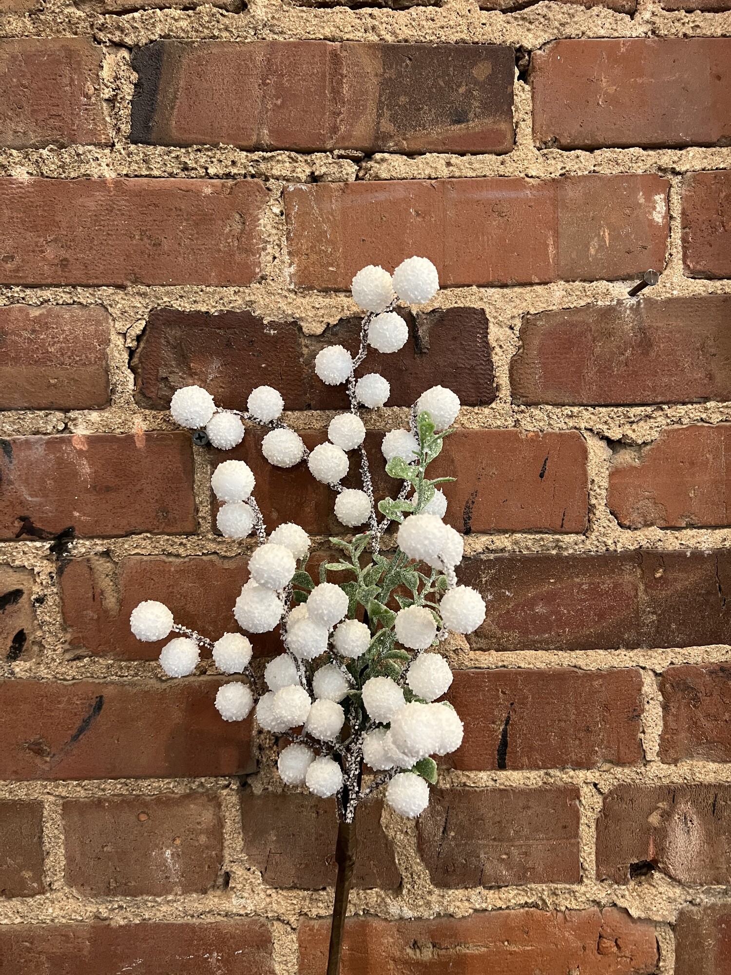 Small Snowballs with a touch of greenery all with a bit of glitter make this a pretty stem to add to any winter decor. Stem measures 18 inches tall
