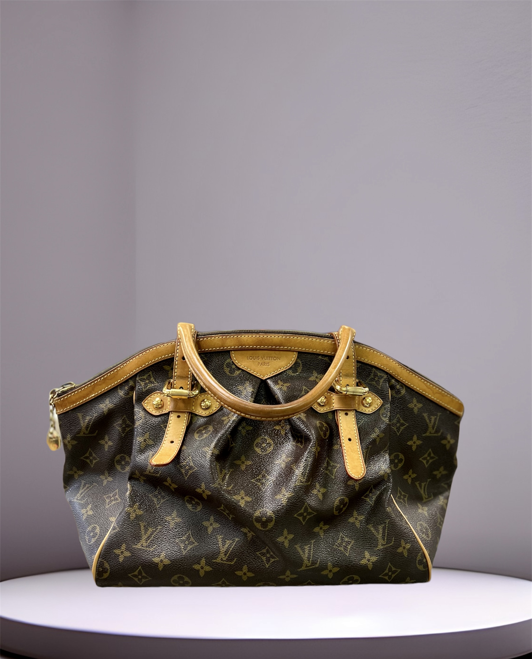 LOUIS VUITTON
MONOGRAM CANVAS TIVOLI GM
Spacious carry-all Tivoli bag from Louis Vuitton rendered in the house's iconic Monogram coated canvas, trimmed with natural Vachetta leather and finished in gold-tone brass hardware.
Features:
Two Rolled Leather Shoulder Straps
Top Zip Closure
Two Interior Slip And Single Pouch Pockets
Coated Canvas
Canvas Lining
Gold Hardware
Details:
Length: 13\" (33 cm)
Height: 11.5\" (29 cm)
Depth: 7\" (17 cm)
Strap Drop: 7\" (17 cm)
Date Code: SP3069
COMES with CERTIFICATE of AUTHENTICITY
This bag is preloved and is good condition.  The coated canvas is in excellent condition, the leather does show signs of wear.  The interior is spotless and clean with no odor.
\"What comes Around Goes Around\"  has this bag in similar condition for 1412.00,  \"Bag Borrow Steal\" has it for 1300.00 and \"Atlanta Luxury Bags\" as this bag for $895.00 in much worst condition.