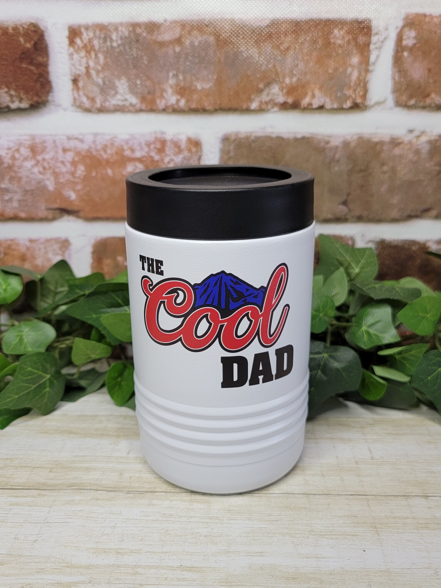Dad will love his new can cooler. Our can coolers are UV Printed with the image shown of the Cool Dad with blue mountains.

Keep your drinks ice cold longer!
- No sweat Exterior
- Hand wash recommended

We UV Print the cups; so there is no worries of a vinyl decal peeling or coming off.