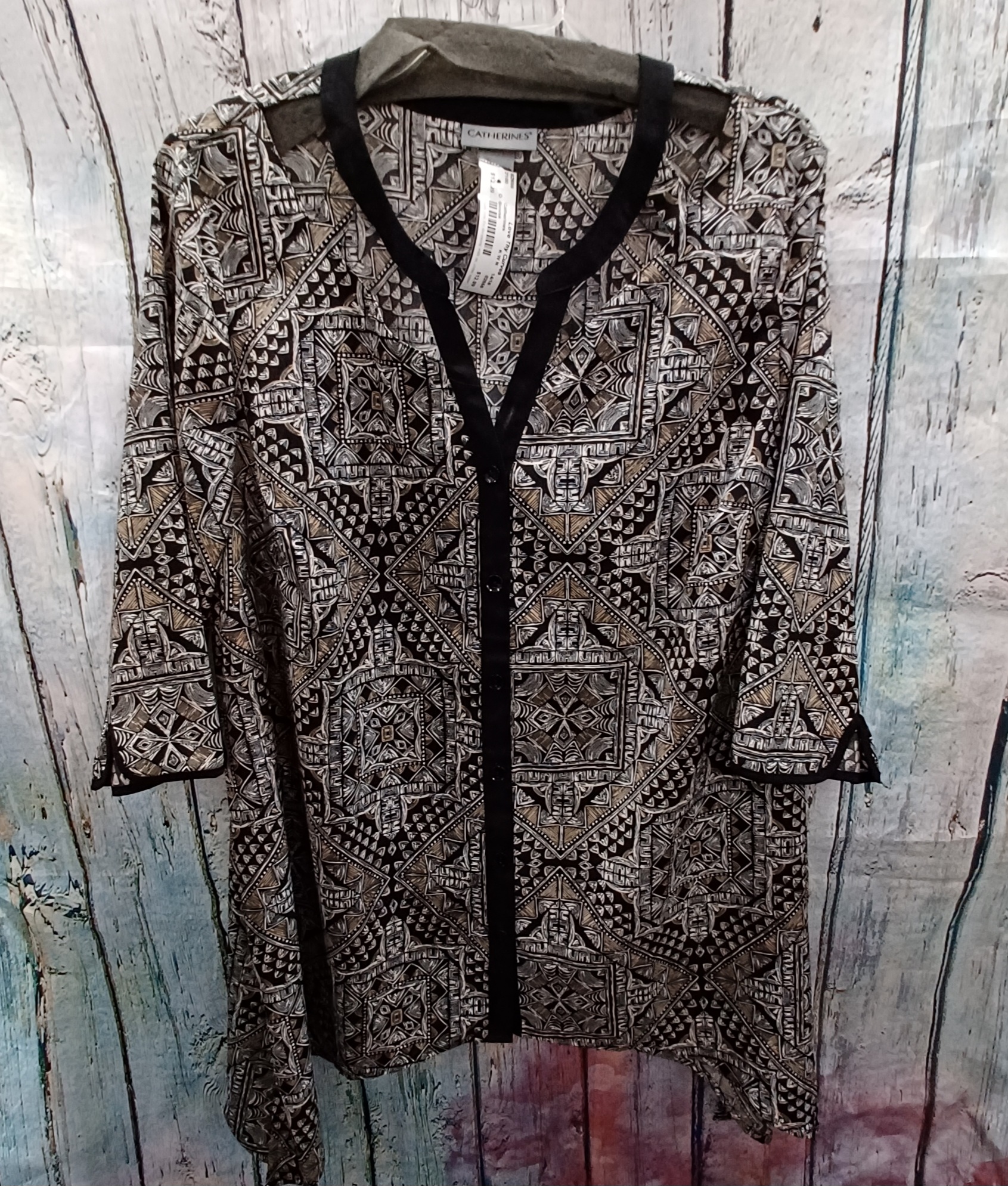 Long tunic style blouse with a half sleeve and button up front done in black, white and tan pattern.