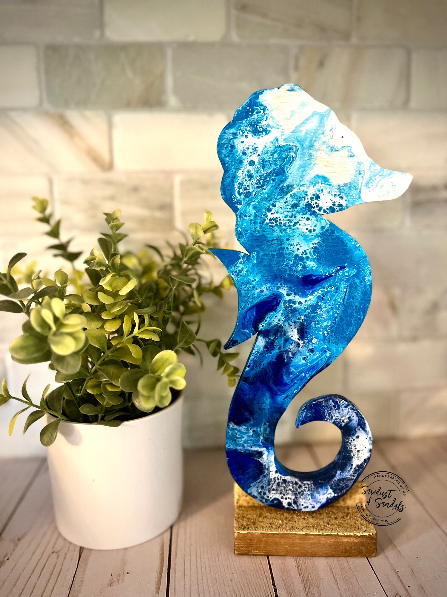 A glimpse of an ocean wave on a hand cut sea horse wooden canvas.   This is Hand cut and Hand painted wood decor.   Made and cut from aged wood; an Ocean wave fluid art is captured on this unique design.  Standing on a base with actual beach sand.
4.5â€x 12â€.   created by a local artist.