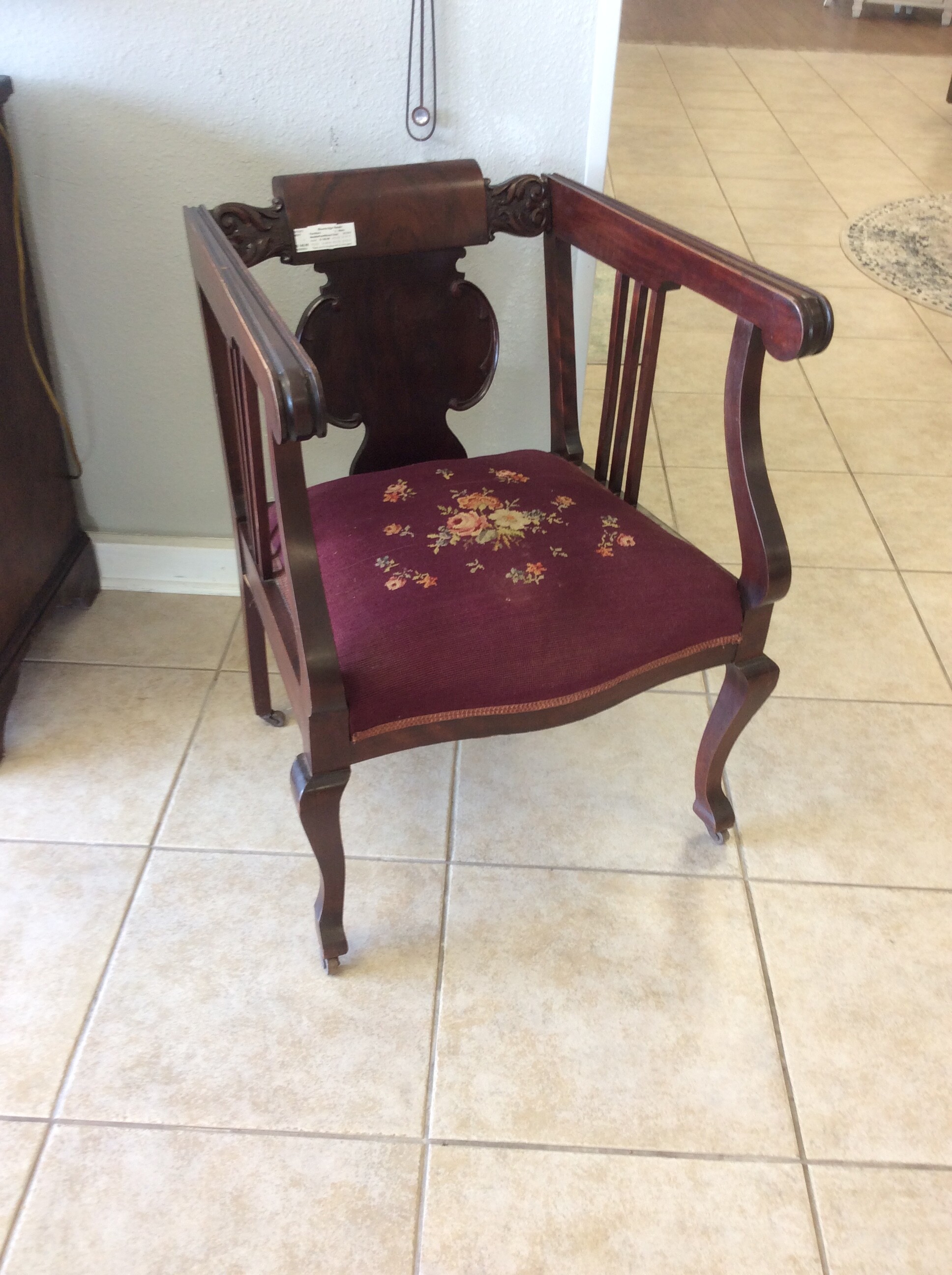 This is a beautiful antique neddle point wood chair. The seat is maroon and has yellow and red roses stitched onto it.