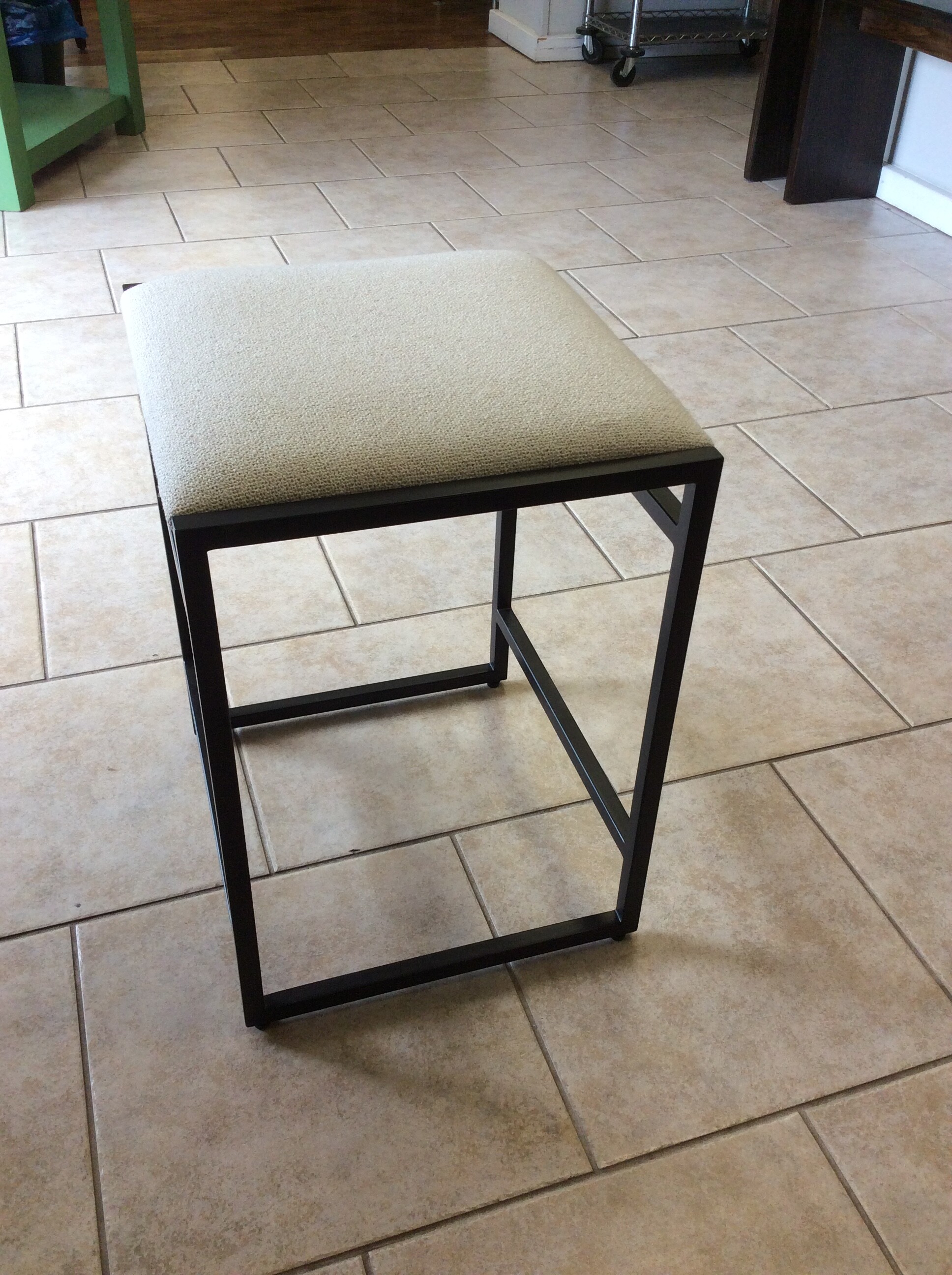 Modern in design, this counter height stool is from Pottery Barn. It features a black metal frame and an off-white upholstered seat,