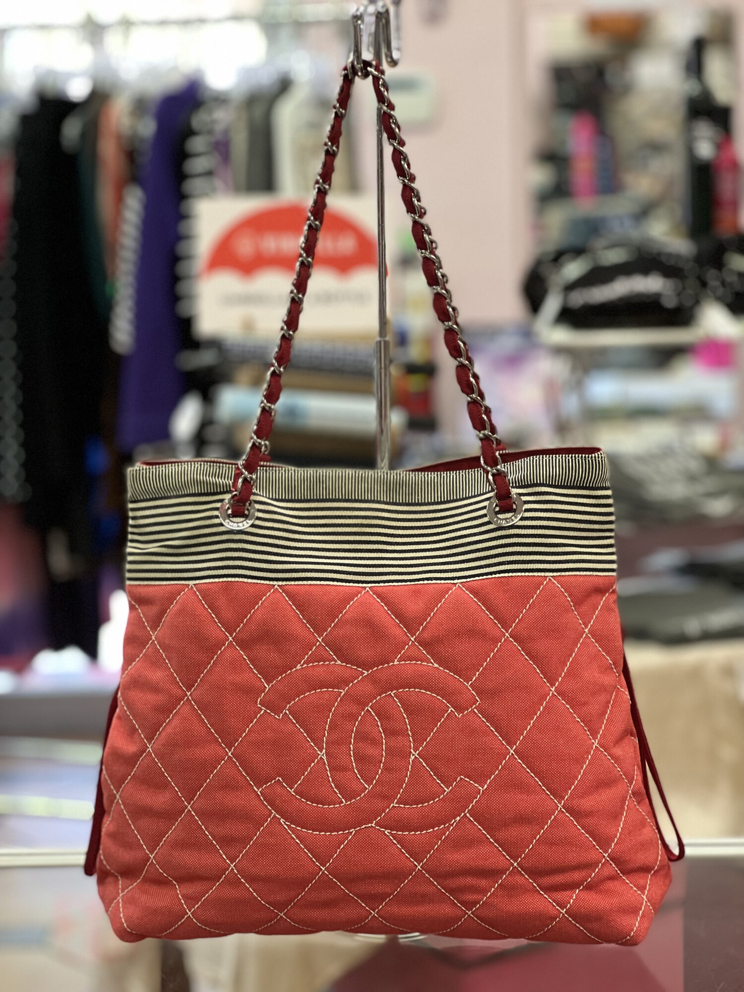 CHANEL

Chanel Red & Stripe Canvas Cruise Line Chain Shoulder Bag with silver-tone hardware, red canvas lining, interior slip and zip pockets, dual chain leather shoulder strap, and zipper closure at the top.
This bag does come with CERTIFICATE OF AUTHENTICITY!
Resale website Grailed has this bag in similar condition for $1895.00 and 1st Dibs ha this for sale for $1516.00

About the Designer
Chanel
In the years following the opening of her modest millinery shop, Gabrielle \"Coco\" Chanel became a pivotal designer of both fashionable casual wear and Paris haute couture as well as an icon and arbiter of 20th-century style with her bob haircut and pearls. Today vintage Chanel handbags, jackets and evening dresses are among the most sought-after clothing and accessories for fashion lovers all over the world.

The first Chanel shop was established in 1910 in Paris on rue Cambon by the young milliner Gabrielle Chanel (1883-1971), who had picked up the nickname \"Coco\" while working as a club singer. The boutique drew the attention of the Parisian fashion elite who popularized her wide-brimmed Chanel Modes hats. Soon she added a sportswear store in the Normandy resort town of Deauville, where Coco set the tone for her defining sense of style, traditionally masculine garments reimagined for feminine shapes, made from simple jersey fabric.

Effortless and elegant, Chanel's designs promoted comfort and grace in women’s wear that had been dominated in the previous century by complicated layers of fabric and cumbersome corsets. She followed this success with a couture house, opened in 1915 in Biarritz.

But Chanel was not born into a life of glamour. Following the death of her mother, her father left her in an orphanage where she lived until the age of 18. It was there that she learned to sew as well as appreciate the classic pairing of black and white as worn by the nuns. In 1926, she introduced her first little black dress, reclaiming a color that had once been reserved for mourning and working-class women. That same decade, she debuted her perfume, Chanel No. 5, as well as the Chanel suit with a fitted skirt, inspired by the boxy lines of men’s clothing and employing a sporty tweed.

Chanel closed her fashion operations during World War II, then returned to the industry in 1954 to design for the functional needs of modern women. Structure and wearability endured in all of Chanel’s clothing and accessories, like the quilted leather 2.55 handbag introduced in 1955 with its gold-chain shoulder strap that freed up a woman’s hands. Chanel's collarless jacket reacted against the constricting styles of Christian Dior's New Look, replacing them with a design that was timeless, an instant classic. The 1957 two-tone slingback pumps had a practical heel height while offering a bold statement in the black tip of the shoes.

After Coco Chanel died in 1971, the brand underwent several changes in leadership, including fashion designer Karl Lagerfeld, who took over as artistic director in 1983. Over the years, the company has continued to innovate, such as expanding into ready-to-wear fashion in 1978 and, in 2002, establishing a subsidiary company  \"Paraffection\" dedicated to preserving the heritage skills of fashion artisan workshops. The House of Chanel still operates its flagship on rue Cambon in Paris, where it all began.