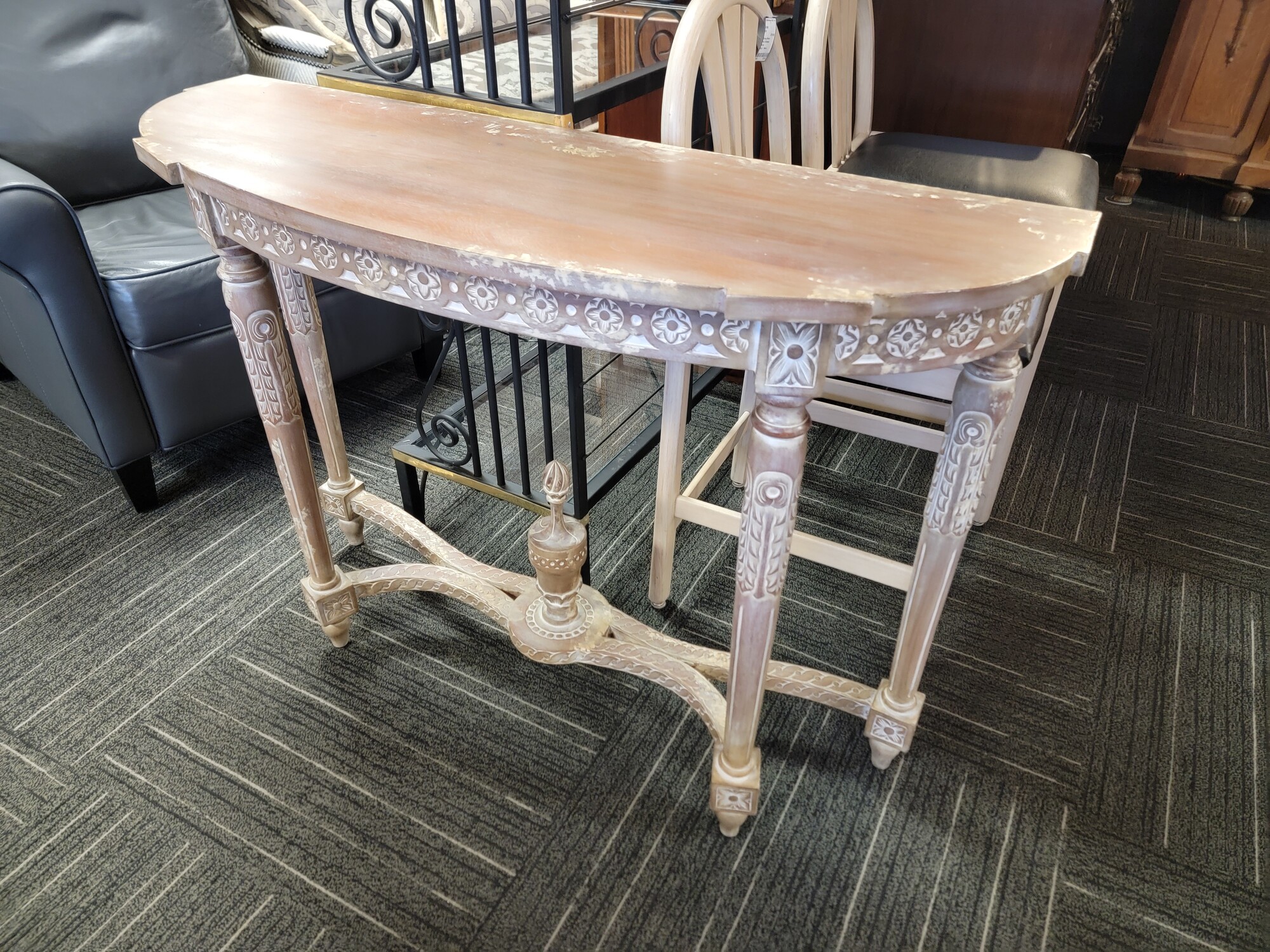 Distressed French Demilune Table in good condition.  Has ornate carvings and a white wash finish.  Measures 43' wide; 14' deep; 31' tall.