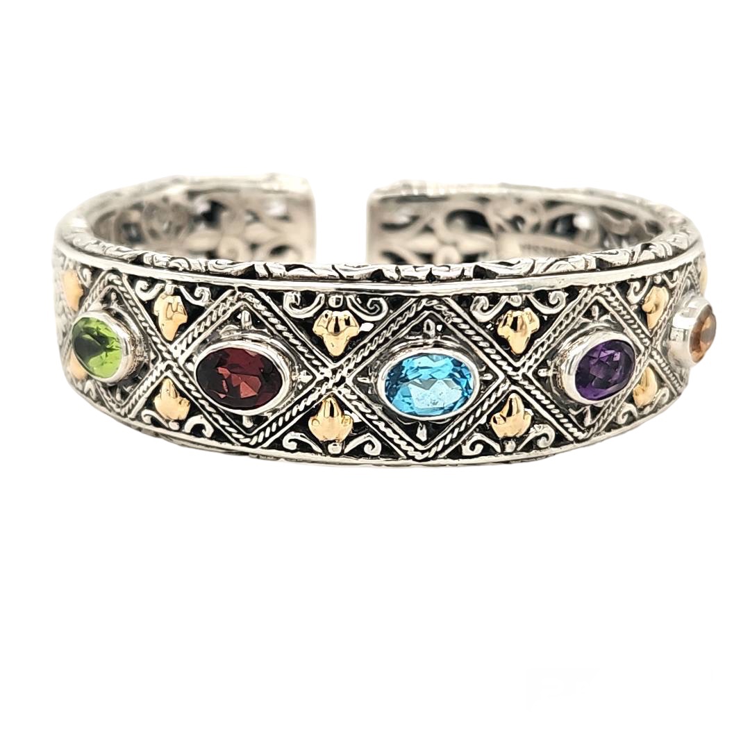 5 Oval Semi Precios Stones Bezel set
atop a Heavyweight Filigree Cuff Bracelet,
Bracelet has hinged opening,
Sterling Silver with18Kt Yellow Gold Accent
Made in Indonesia