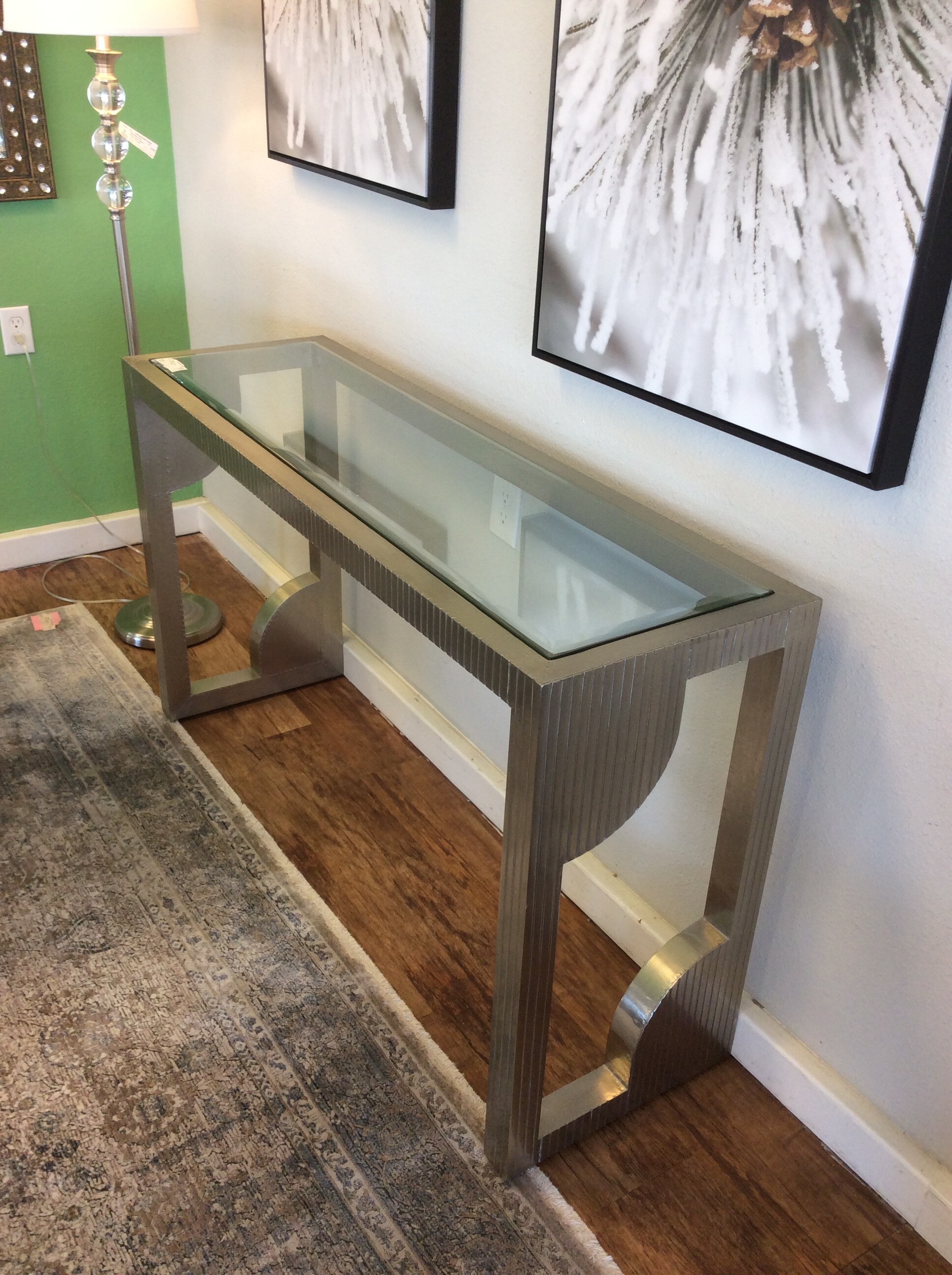 This contemporary style console table has a silver metal finish and a geometric design.