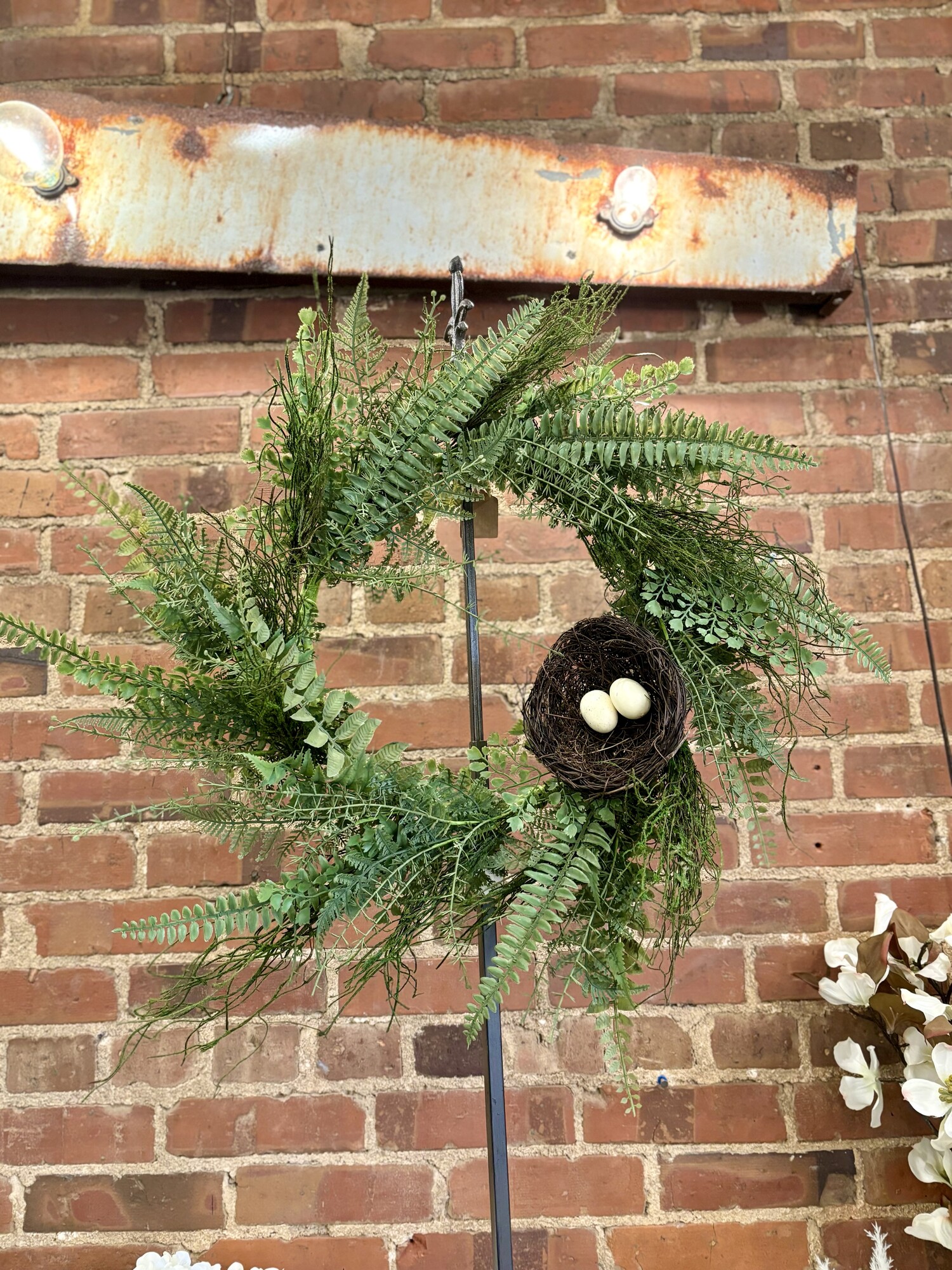 The Mossy Fern Wreath is a beautiful green wreath with a natural base. The wreath is filled wih rustic moss and light green fern stems, complete with a twig nest filled with a pair of cream colored eggs. This wreath brings a whimsical, woodsy touch to your home during the spring.
Wreath measures 10.5 inner diameter and approx 24 to 26 inches outer diameter