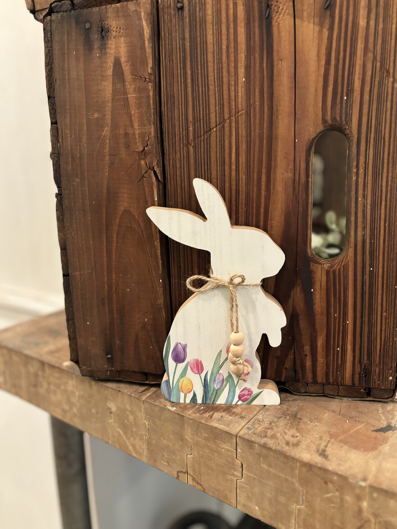 The Tulip Bunny is an adorable addiition to your spring and Easter decor. The bunny is painted a distressed white and has colorful tulips with a jute rope and beads tied around his neck. This bunny measures 8 inches high by 4.5 inches wide and .75 in deep